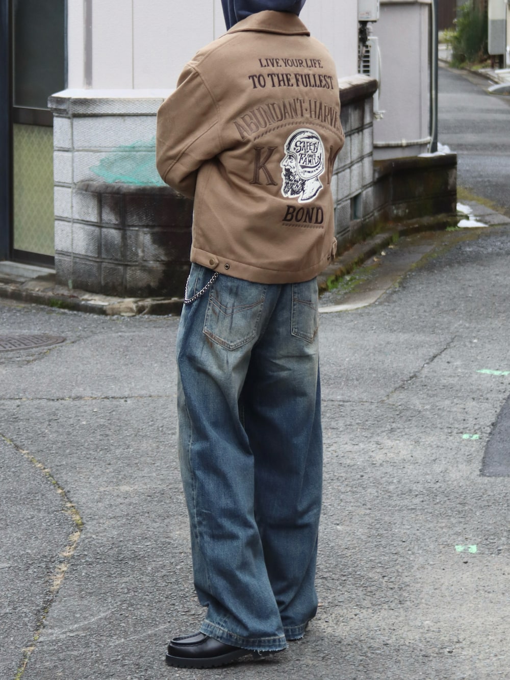 イエロー系のブルゾン、ブルー系のパーカー、ブラック系のドレスシューズを着用したメンズの冬コーディネートの4枚目の写真