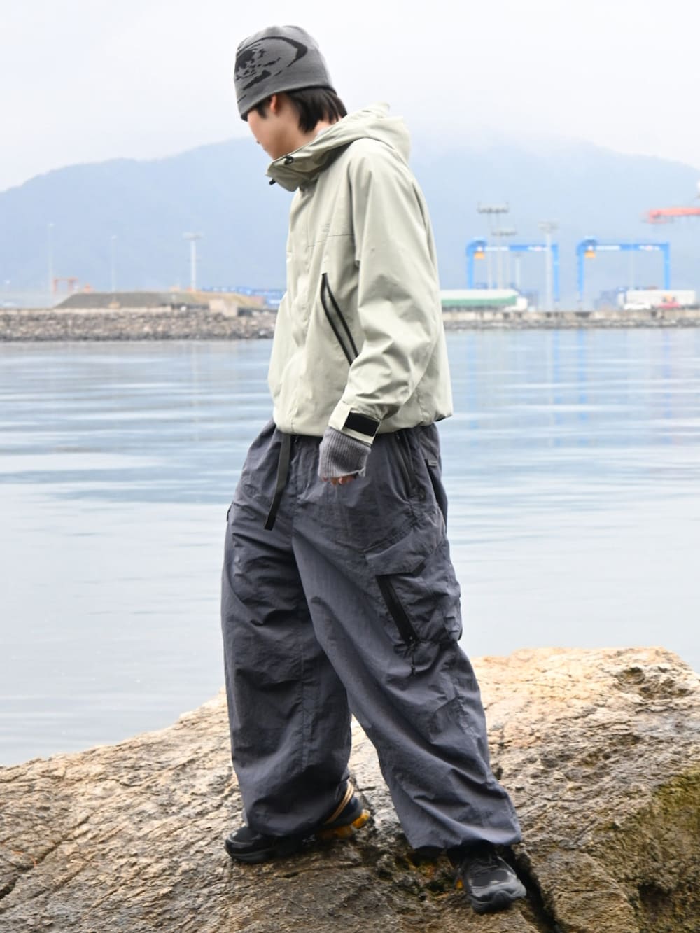 グリーン系のマウンテンパーカー、グレー系のカーゴパンツ、ブラック系のスニーカーを着用したメンズの春コーディネートの4枚目の写真