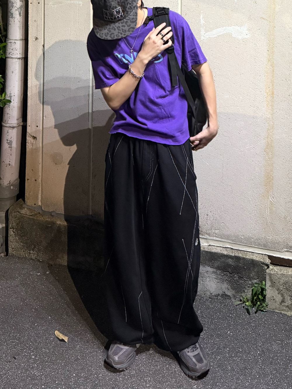 グレー系のスニーカー、パープル系のTシャツ/カットソー、ブラック系のスウェットパンツを着用したメンズの秋コーディネートの3枚目の写真