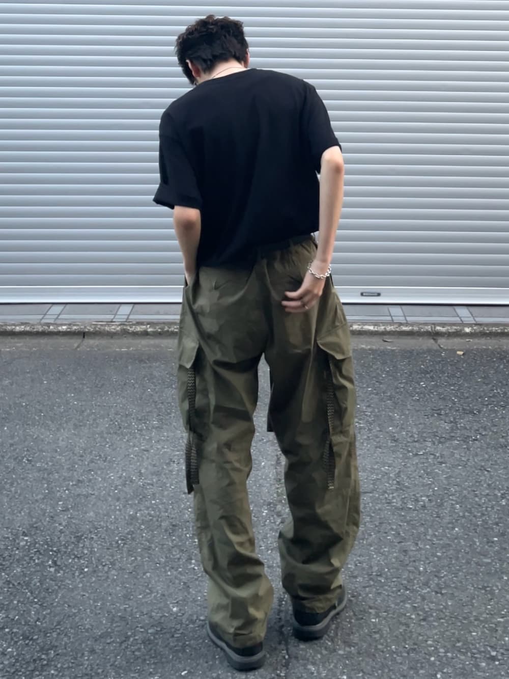 グリーン系のカーゴパンツ、ブラック系のTシャツ/カットソー、ブラック系のブーツを着用したメンズの夏コーディネートの3枚目の写真