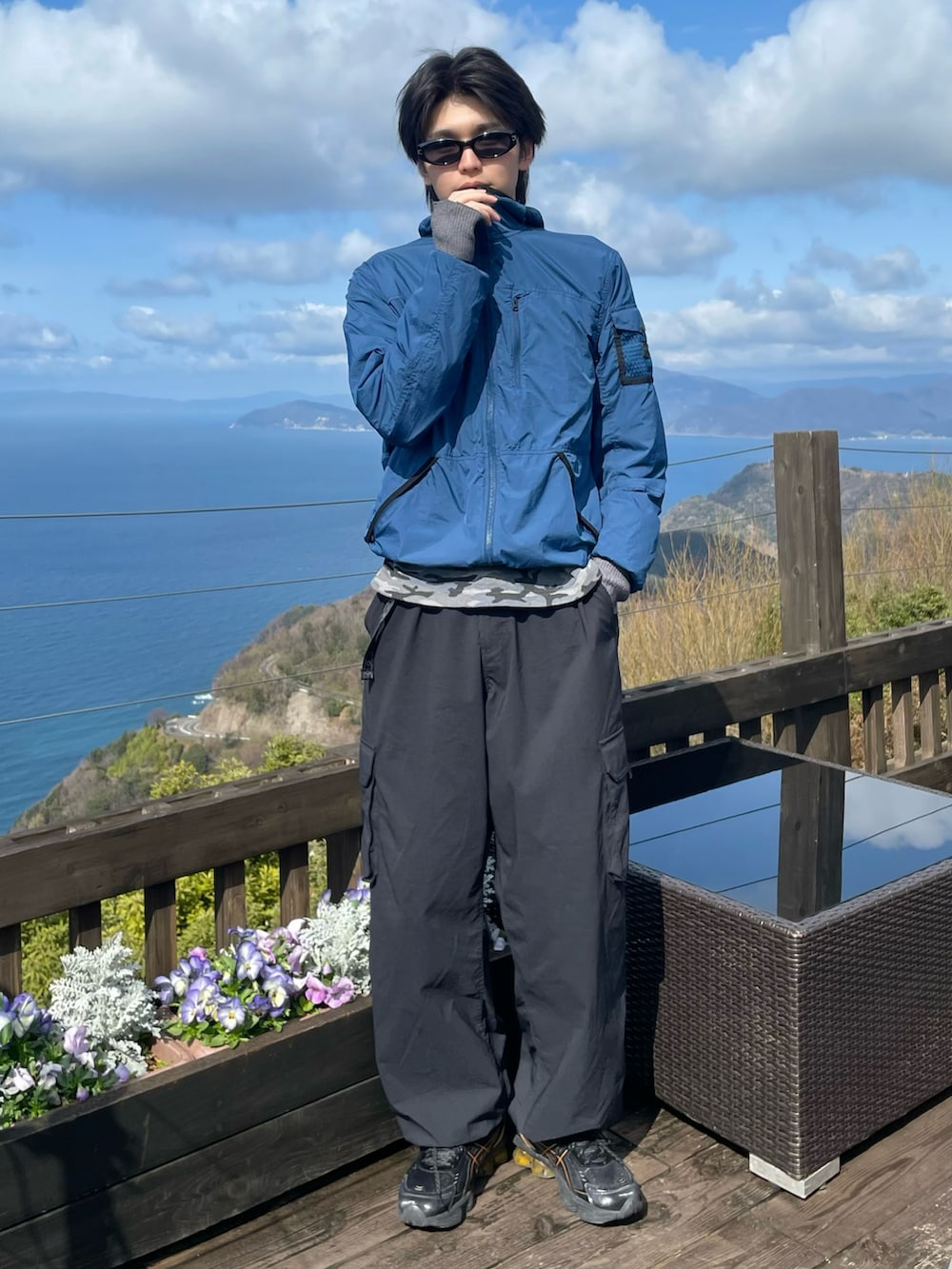 ブルー系のナイロンジャケット、グレー系のTシャツ/カットソー、ブラック系のカーゴパンツを着用したメンズの春コーディネートの2枚目の写真