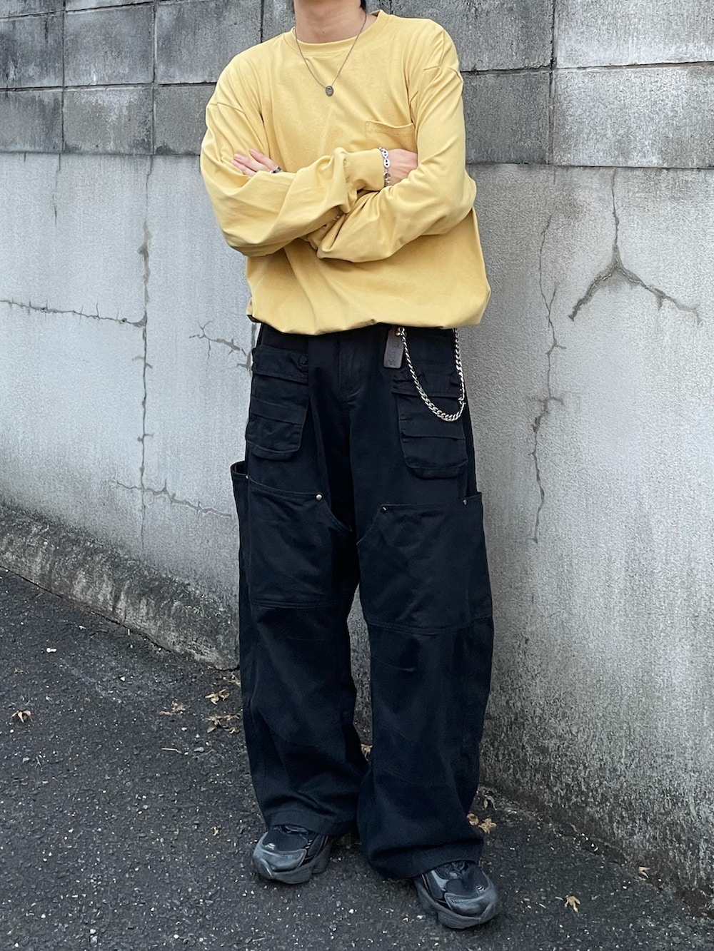 イエロー系のTシャツ/カットソー、ブラック系のカーゴパンツ、ブラック系のスニーカーを着用したメンズの秋コーディネートの3枚目の写真