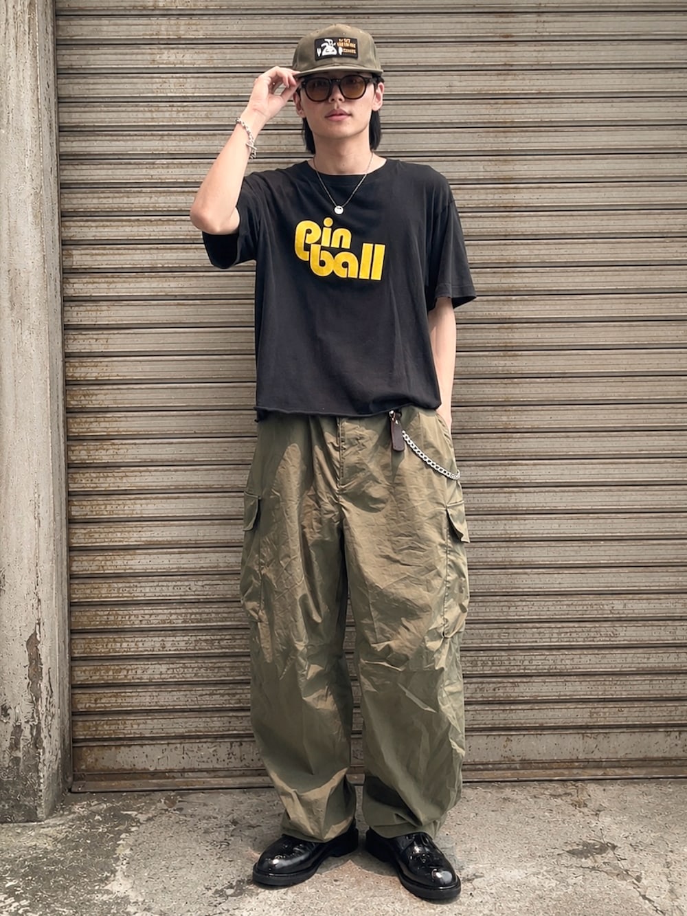 ブラック系のドレスシューズ、グリーン系のカーゴパンツ、ブラック系のTシャツ/カットソーを着用したメンズの夏コーディネートの2枚目の写真