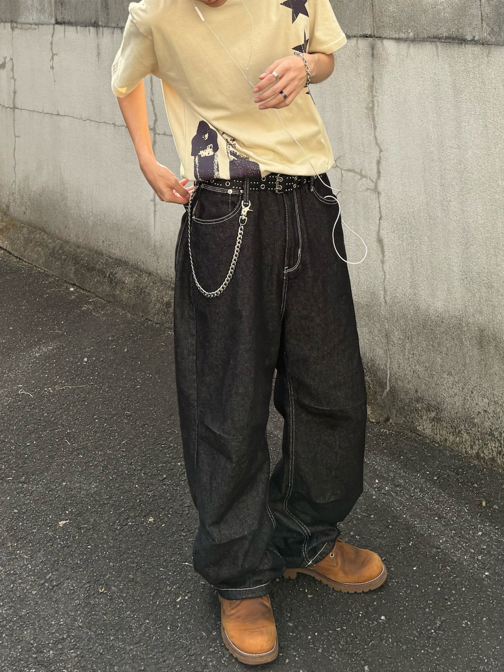 ベージュ系のTシャツ/カットソー、ブラック系のデニムパンツ、オレンジ系のブーツを着用したメンズの夏コーディネートの3枚目の写真