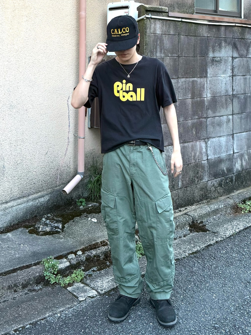 ブラック系のTシャツ/カットソー、グリーン系のカーゴパンツ、ブラック系のブーツを着用したメンズの秋コーディネートの2枚目の写真