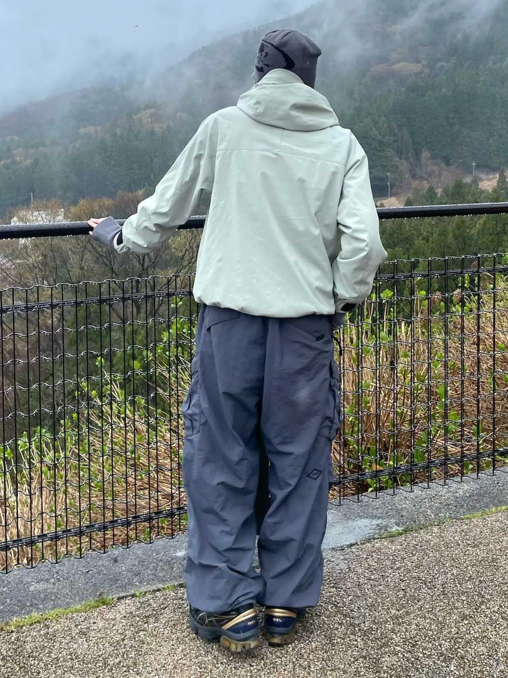 グリーン系のマウンテンパーカー、グレー系のカーゴパンツ、ブラック系のスニーカーを着用したメンズの春コーディネートの3枚目の写真