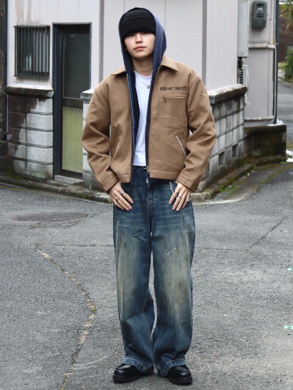 イエロー系のブルゾン、ブルー系のパーカー、ブラック系のドレスシューズを着用したメンズの冬コーディネートの3枚目の写真