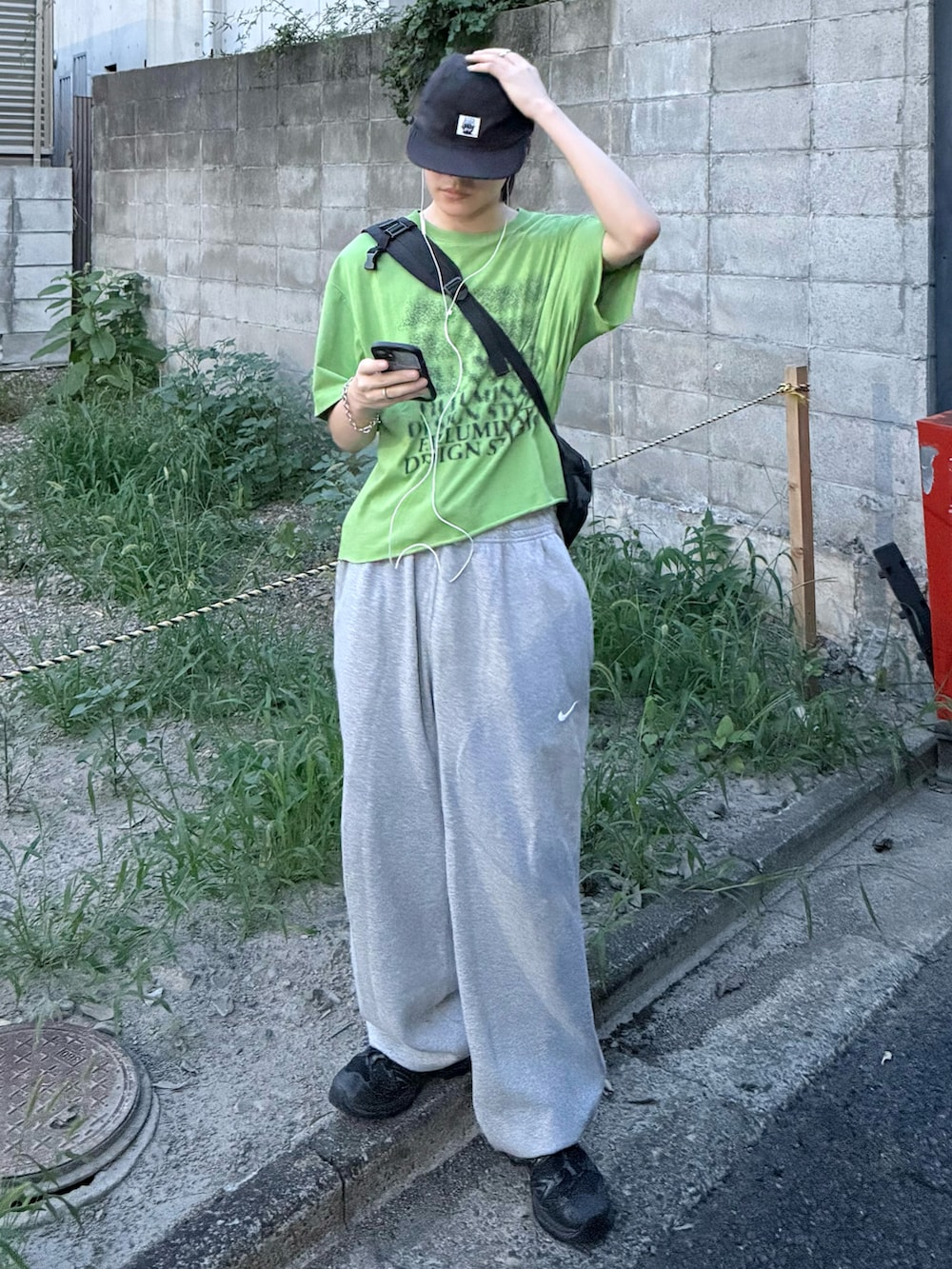 ブラック系のスニーカー、グリーン系のTシャツ/カットソー、グレー系のスウェットパンツを着用したメンズの秋コーディネートの2枚目の写真