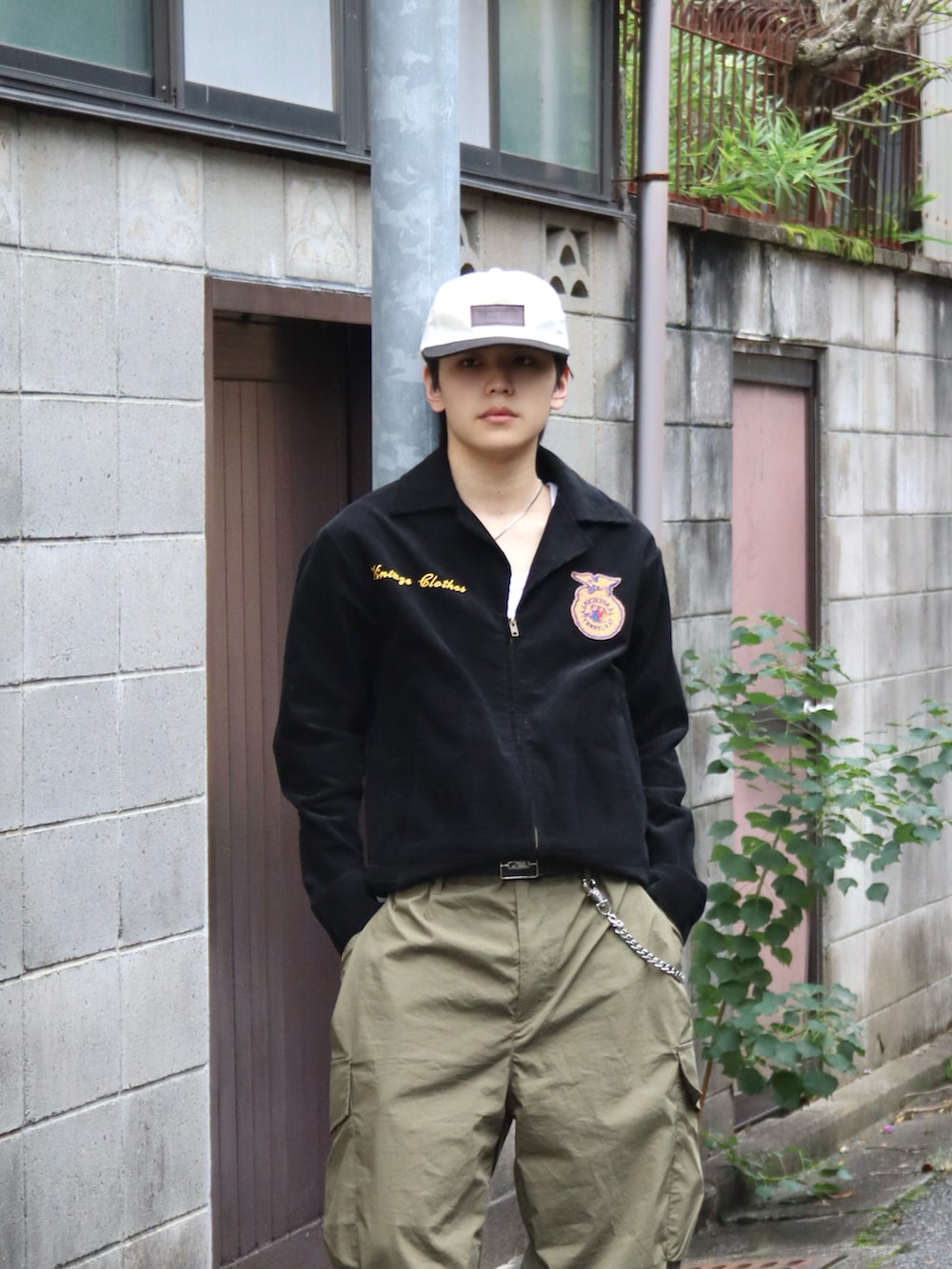 ホワイト系のタンクトップ、グリーン系のカーゴパンツ、ブラック系のミリタリージャケットを着用したメンズの秋コーディネートの3枚目の写真