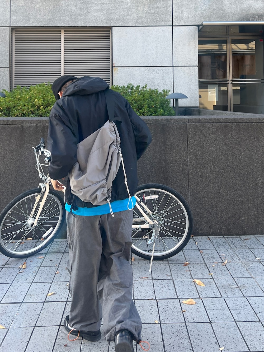 ブラック系のマウンテンパーカー、グレー系のパンツ、ブラック系のローファーを着用したメンズの秋コーディネートの2枚目の写真