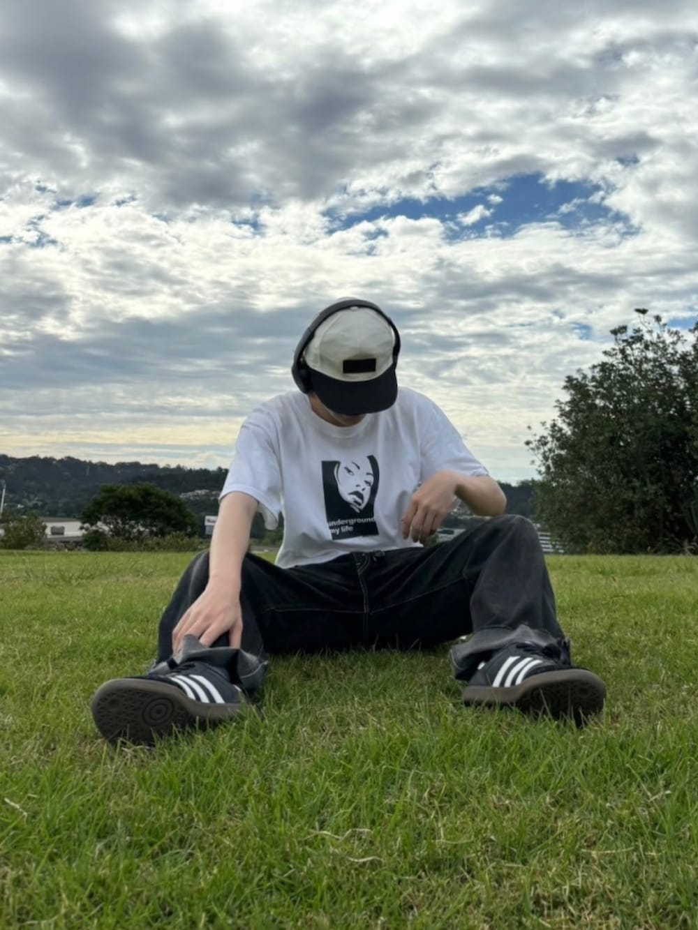 ブラック系のスニーカー、ホワイト系のTシャツ/カットソー、ブラック系のデニムパンツを着用したメンズの夏コーディネートの2枚目の写真