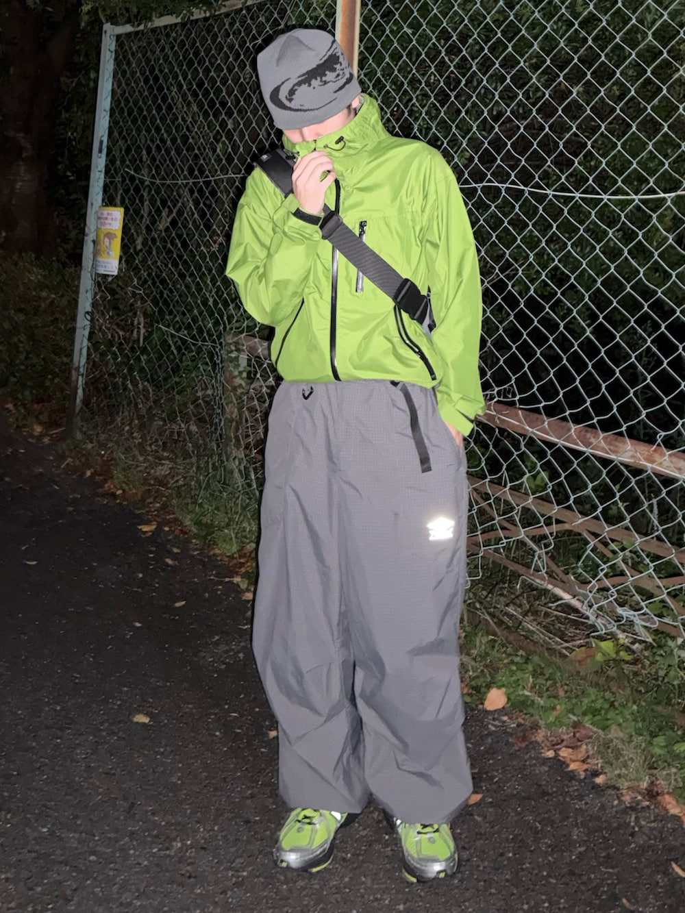 グレー系のカーゴパンツ、グリーン系のスニーカー、グリーン系のマウンテンパーカーを着用したメンズの秋コーディネートの3枚目の写真