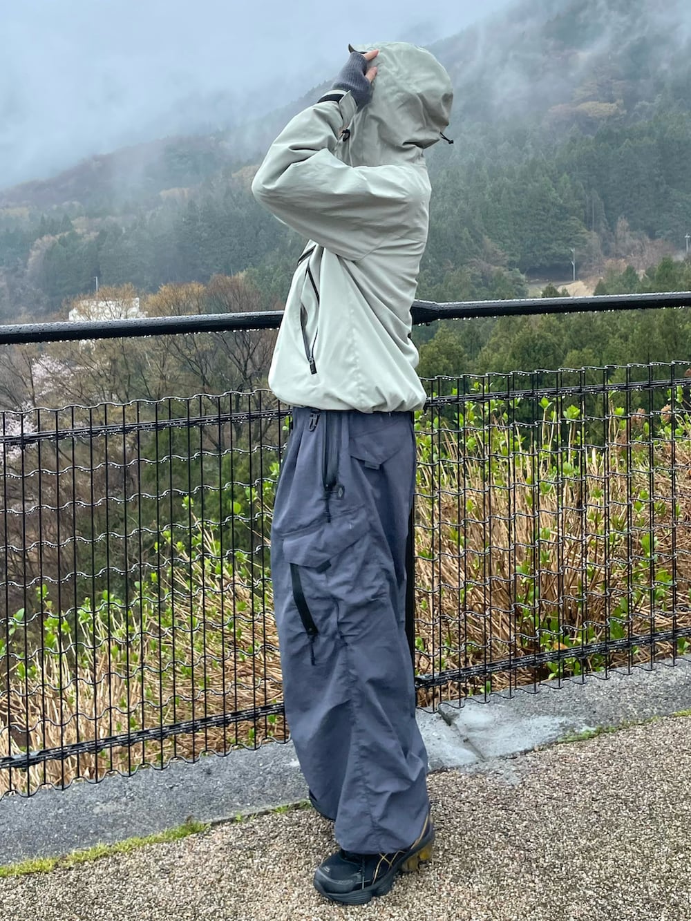 グリーン系のマウンテンパーカー、グレー系のカーゴパンツ、ブラック系のスニーカーを着用したメンズの春コーディネートの2枚目の写真