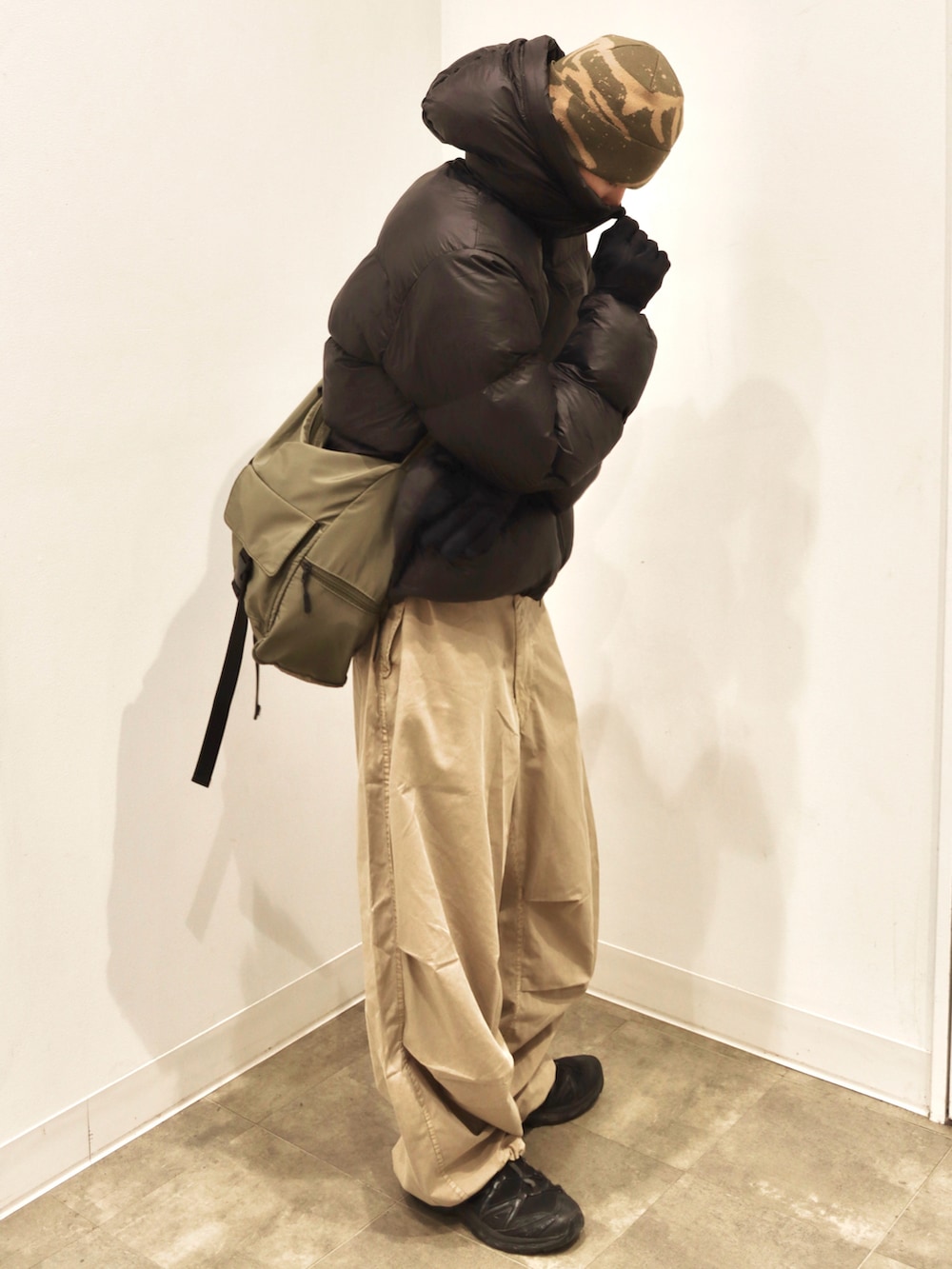 ベージュ系のカーゴパンツ、グリーン系のショルダーバッグ、ブラック系のスニーカーを着用したメンズの冬コーディネートの3枚目の写真