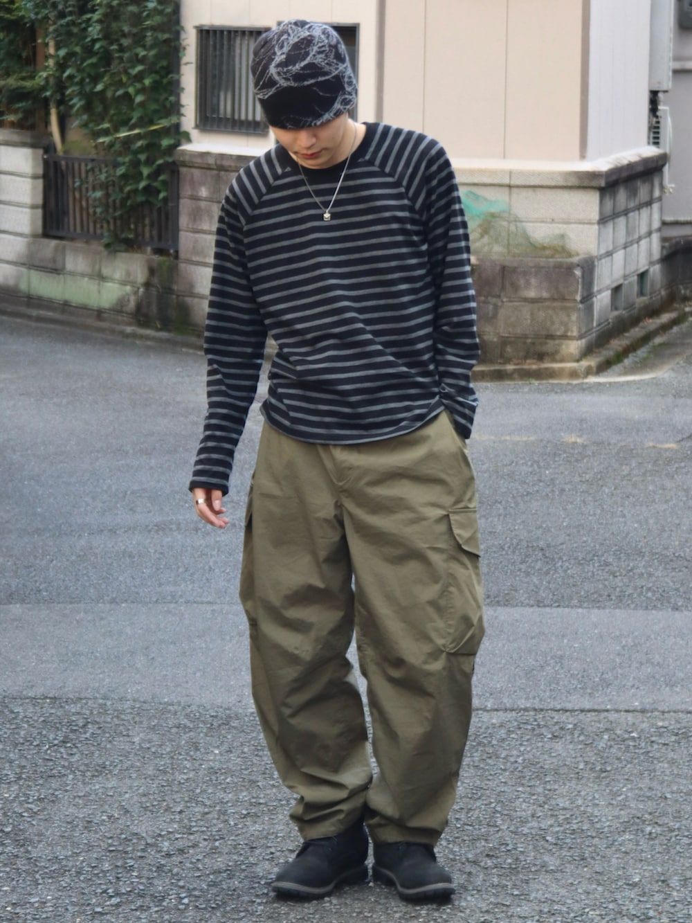 グリーン系のカーゴパンツ、ブラック系のブーツ、その他のTシャツ/カットソーを着用したメンズの秋コーディネートの3枚目の写真