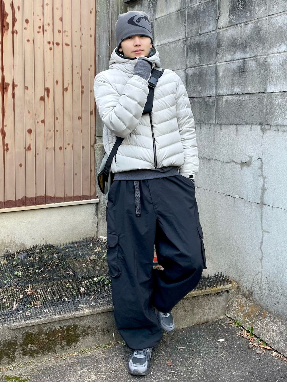 グレー系のスウェット、グレー系のメッセンジャーバッグ、ブラック系のカーゴパンツを着用したメンズの冬コーディネートの2枚目の写真