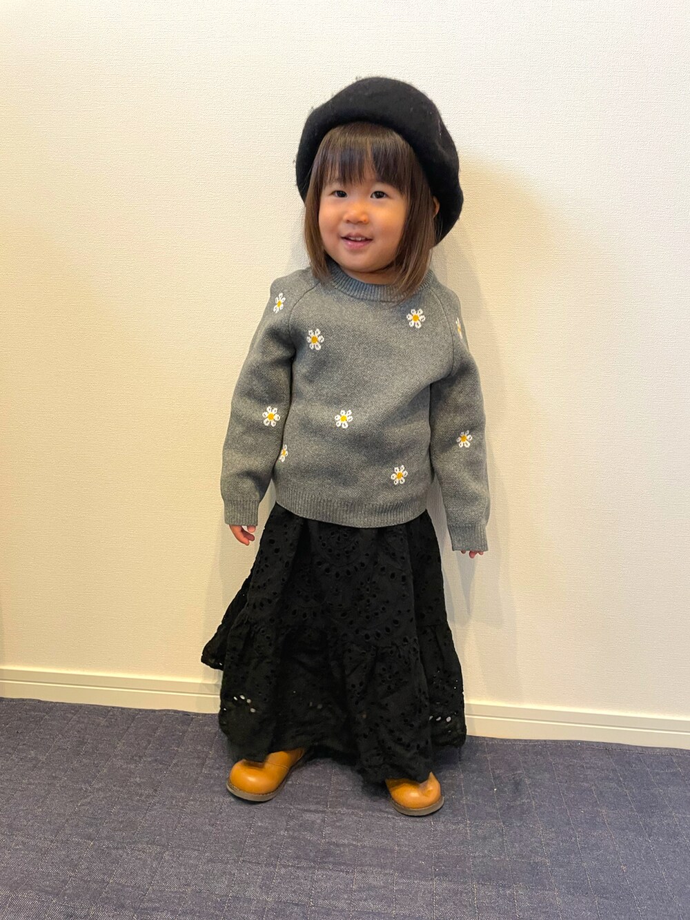 グレー系のトップス、ブラック系のスカート、ブラウン系のスニーカーを着用したキッズの冬コーディネートの2枚目の写真