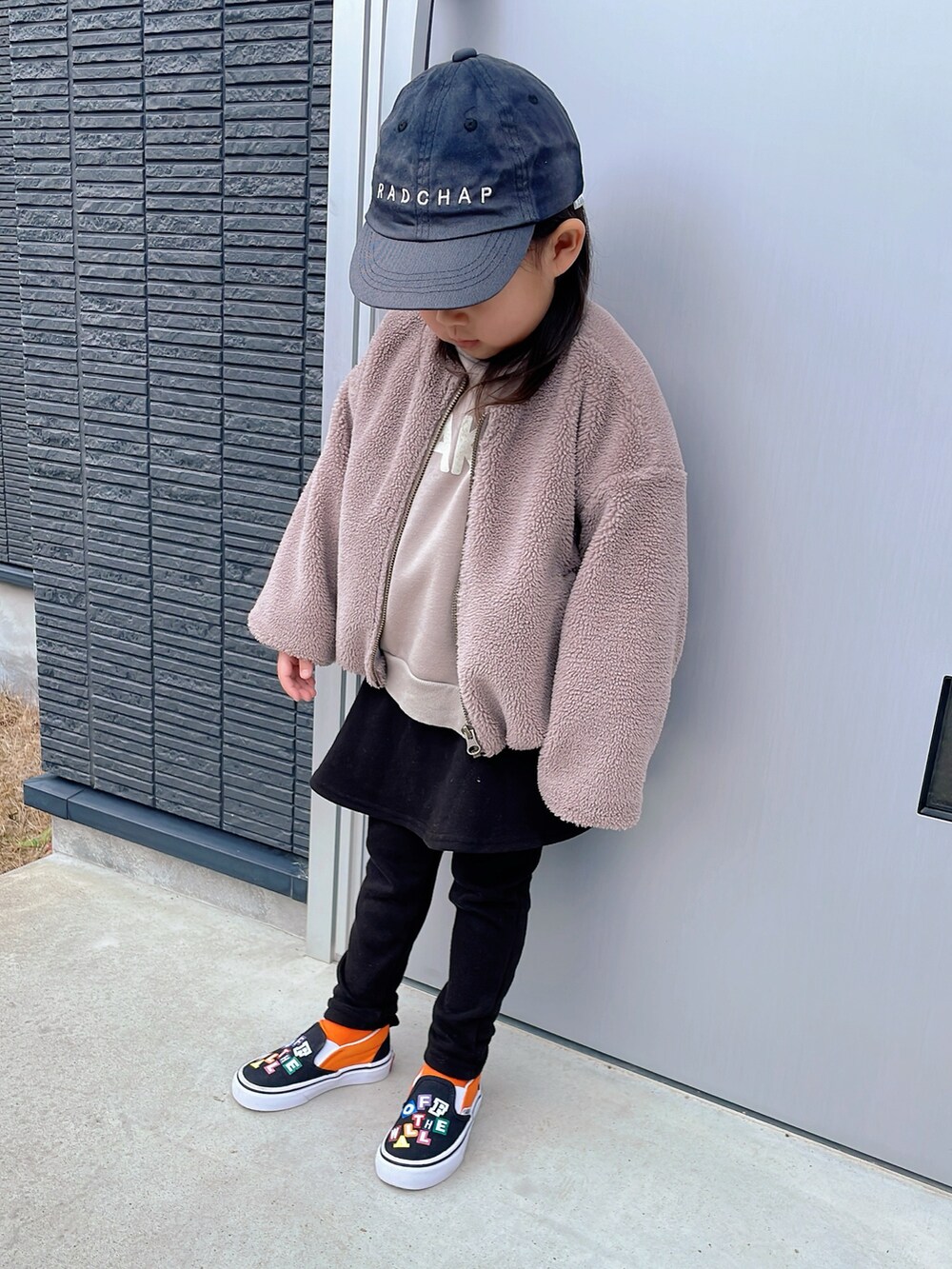 ブラウン系のノーカラージャケット、ベージュ系のスウェット、ブラック系のスカートを着用したキッズの冬コーディネートの2枚目の写真