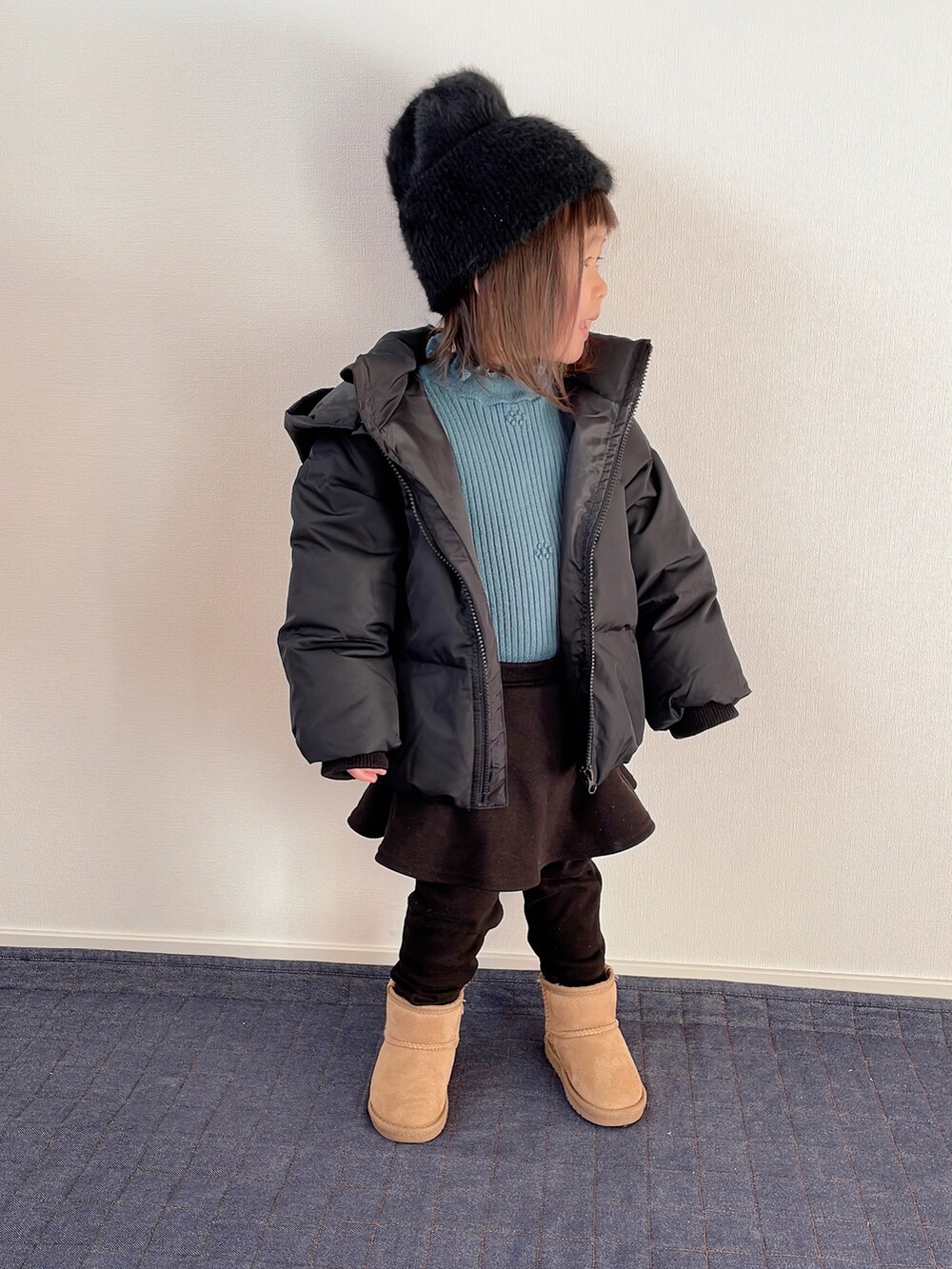 グリーン系のニット/セーター、ブラック系のブルゾン、ブラック系のスカートを着用したキッズの冬コーディネートの2枚目の写真