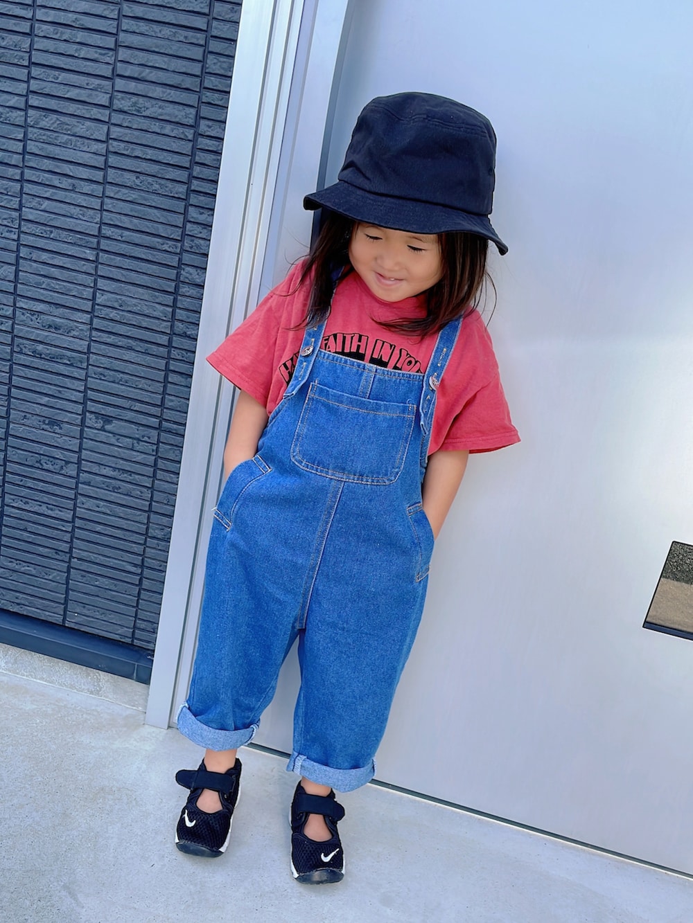 レッド系のTシャツ/カットソー、ブラック系のスニーカー、ブラック系のハットを着用したキッズの秋コーディネートの2枚目の写真