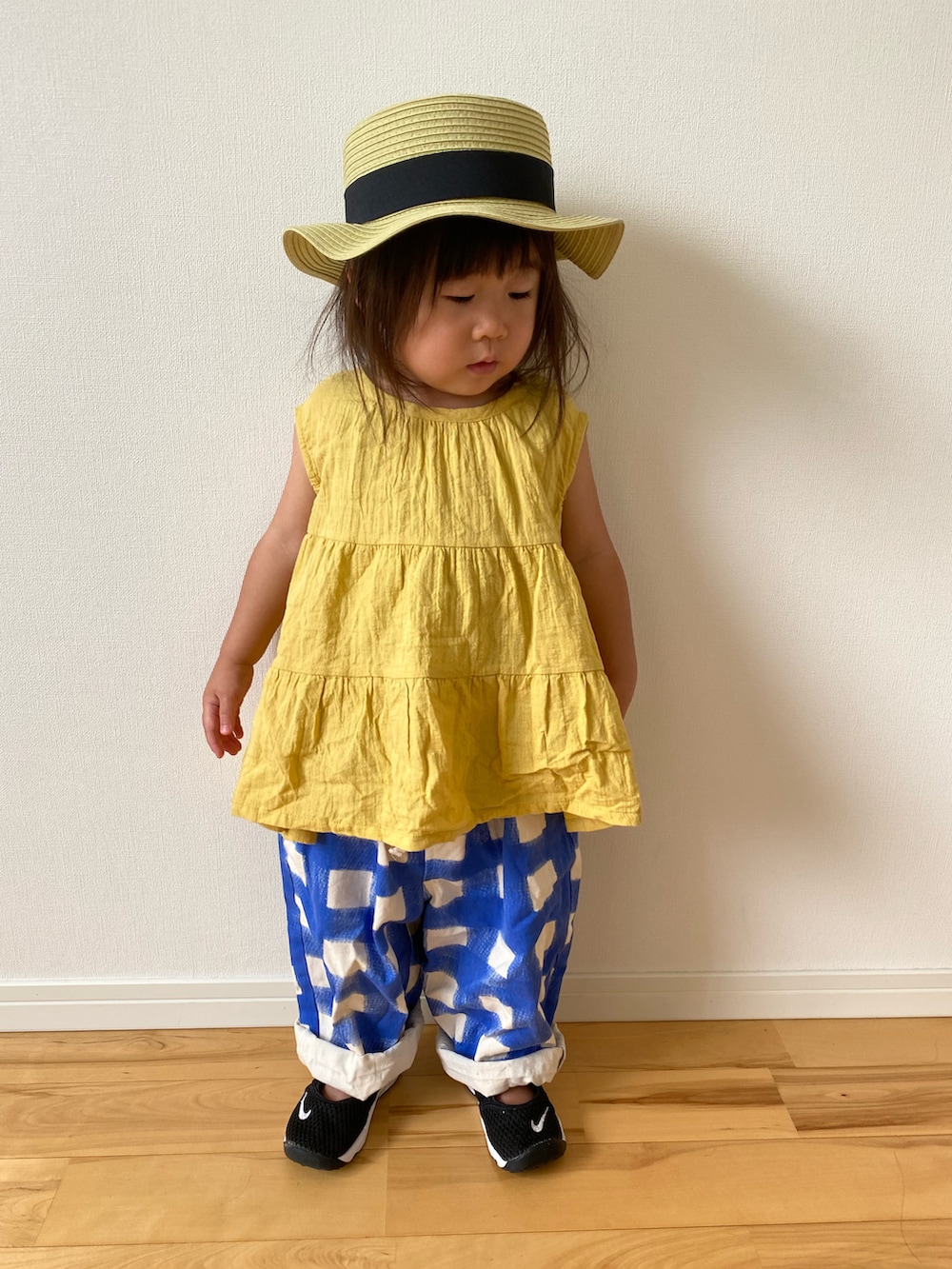 イエロー系のチュニック、ブルー系のその他パンツ、ブラック系のスニーカーを着用したキッズの夏コーディネートの2枚目の写真