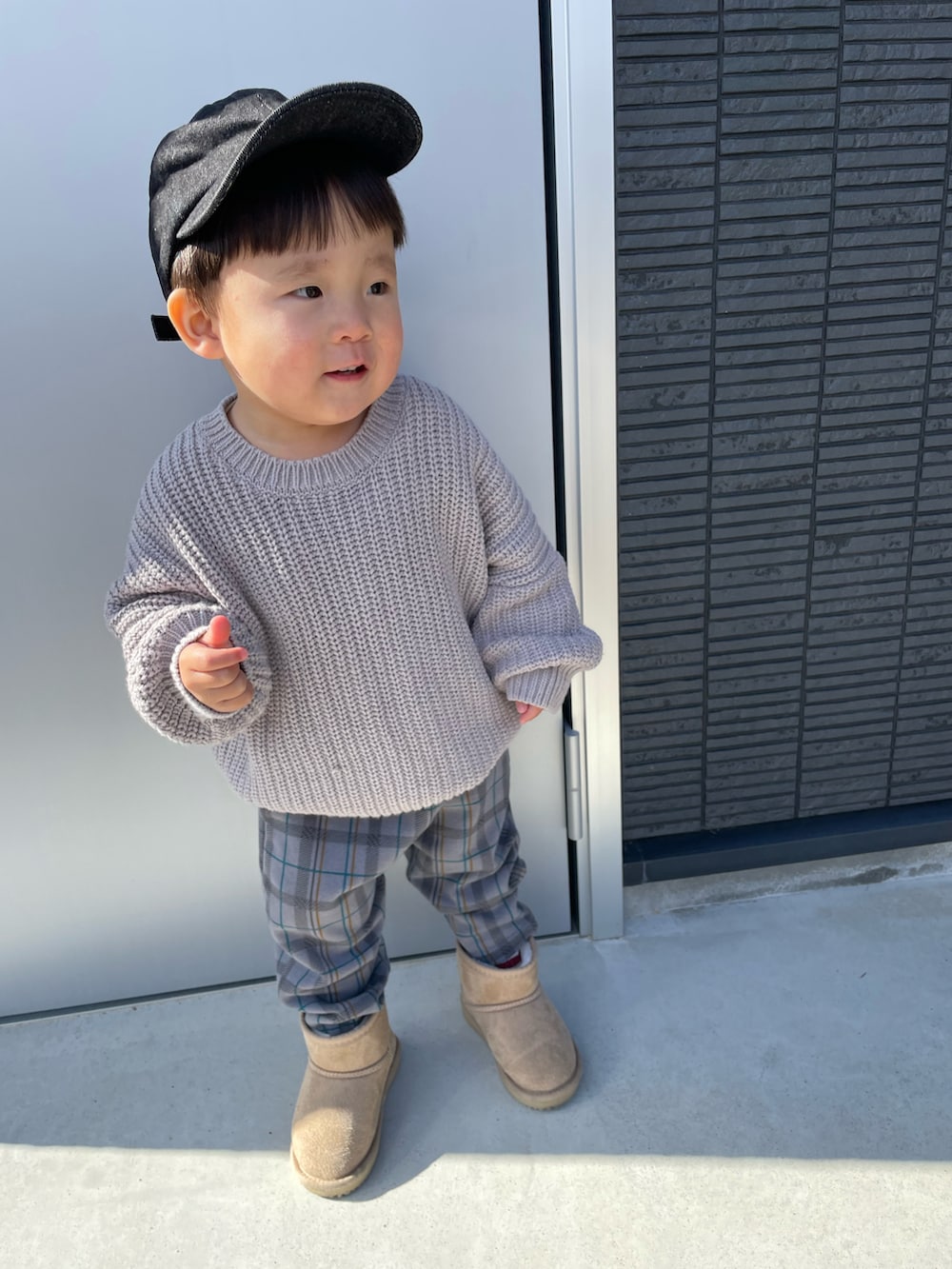 グレー系のニット/セーター、グレー系のその他パンツ、ベージュ系のブーツを着用したキッズの冬コーディネートの2枚目の写真