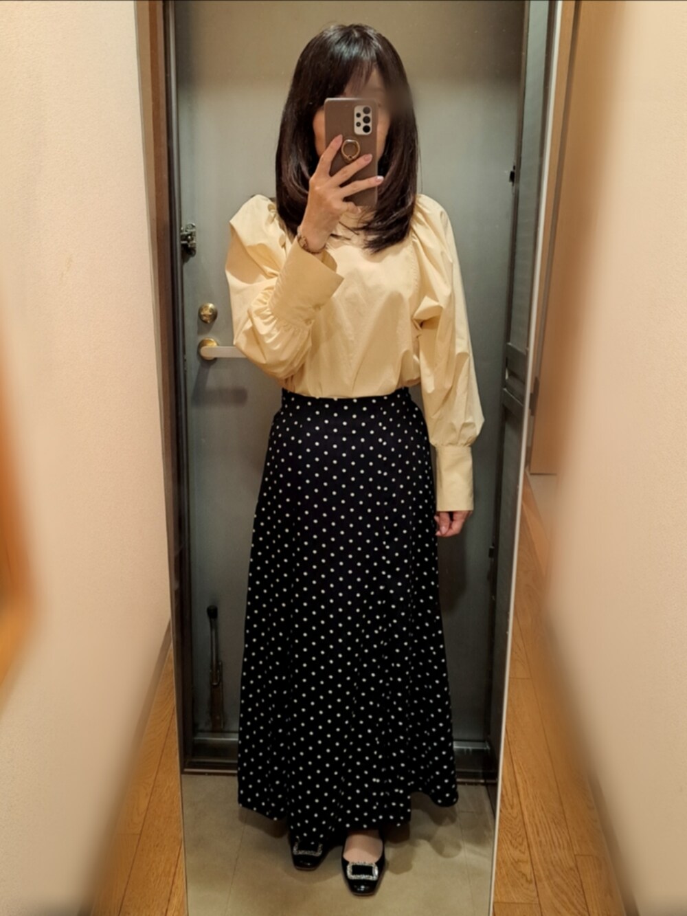 ホワイト系のスカート、イエロー系のシャツ/ブラウス、ブラック系のカーディガン/ボレロを着用したレディースの春コーディネートの2枚目の写真