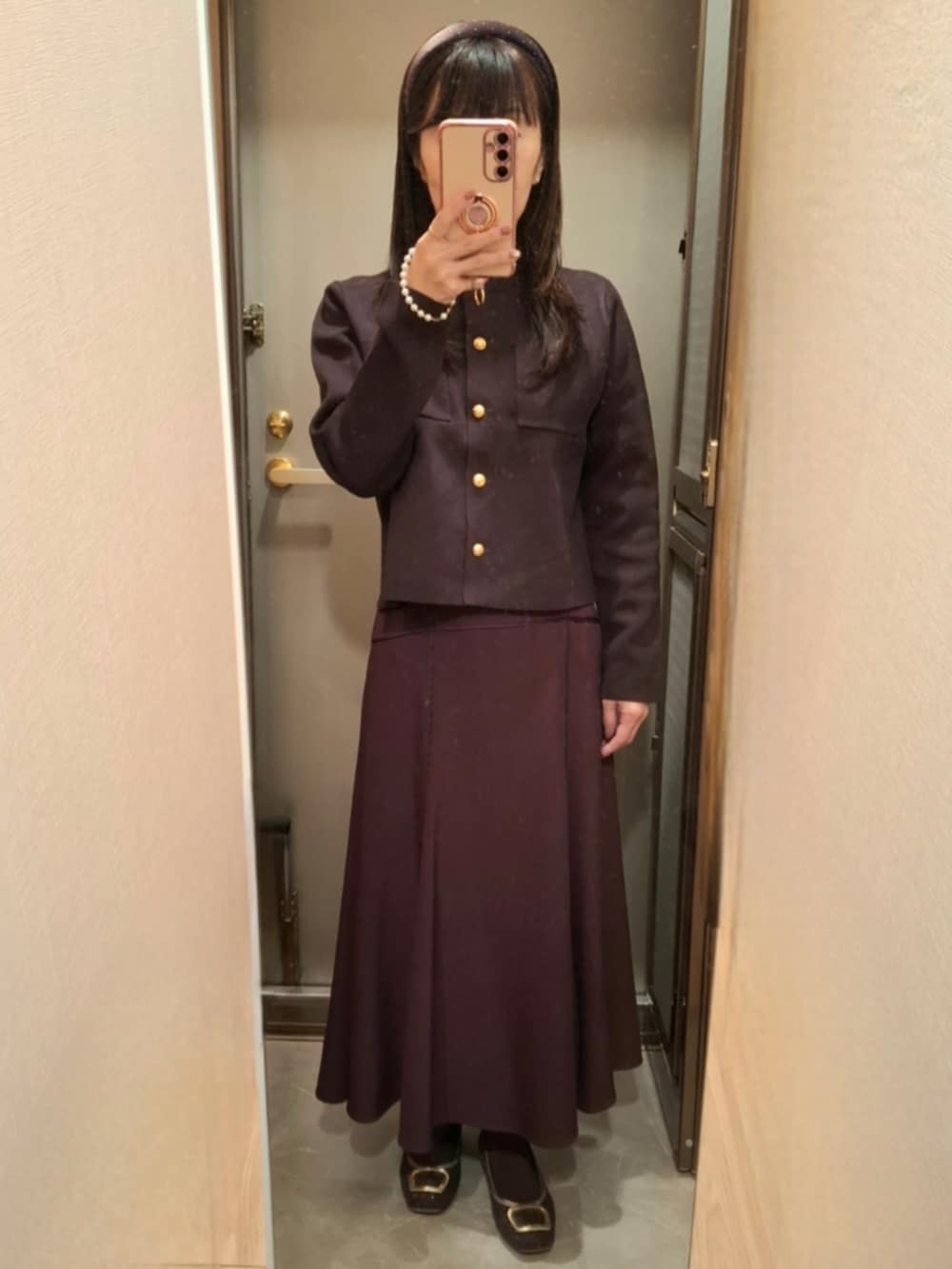 ブラウン系のテーラードジャケット、ブラウン系のカーディガン/ボレロ、レッド系のスカートを着用したレディースの秋コーディネートの2枚目の写真