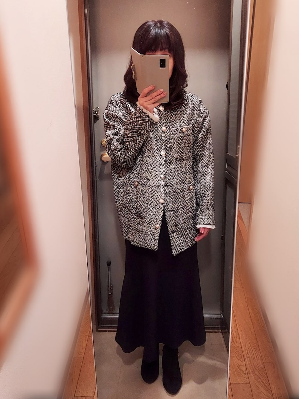 ブラック系のノーカラージャケット、ブラック系のジャンパースカート、ブラック系のブーツを着用したレディースの秋コーディネートの3枚目の写真