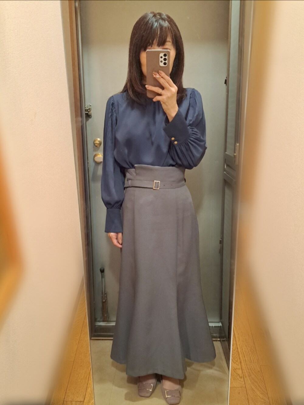 グレー系のスカート、グレー系のカーディガン/ボレロ、ブルー系のシャツ/ブラウスを着用したレディースの秋コーディネートの2枚目の写真