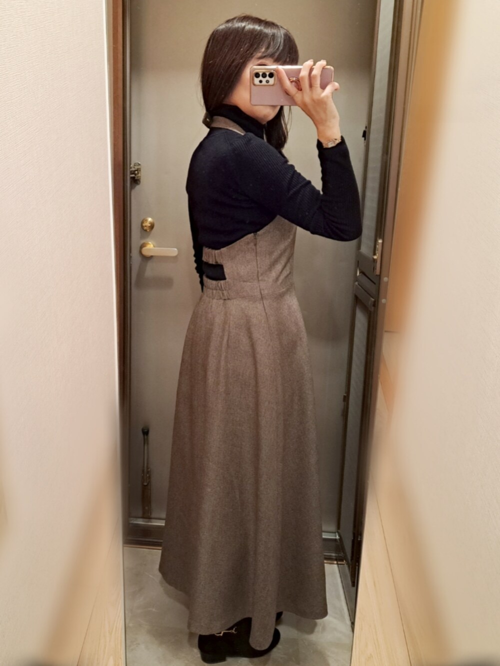 ブラウン系のブーツ、ブラウン系のジャンパースカート、ブラック系のニット/セーターを着用したレディースの冬コーディネートの2枚目の写真