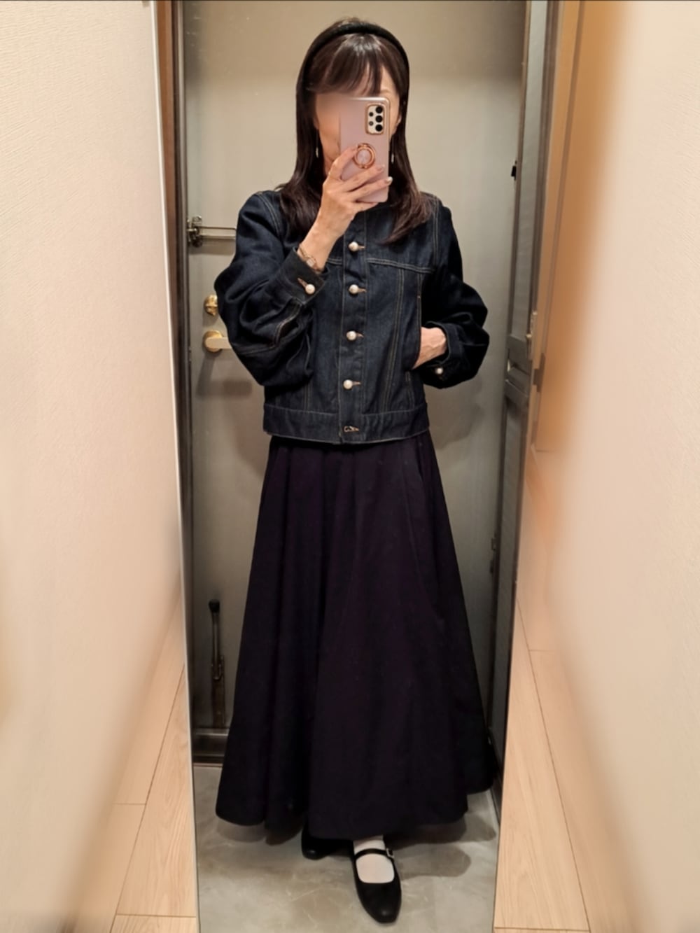 ブルー系のデニムジャケット、ブラック系のスカート、ブラック系のパンプスを着用したレディースの秋コーディネートの2枚目の写真