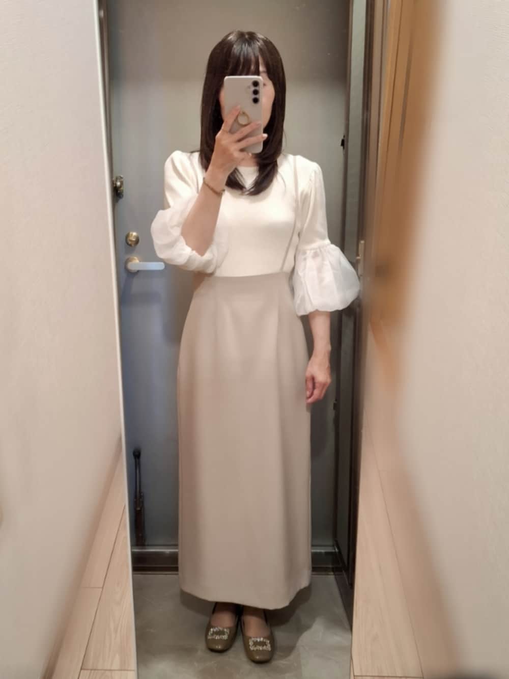 ブラウン系のパンプス、ベージュ系のスカート、ホワイト系のニット/セーターを着用したレディースの春コーディネートの2枚目の写真
