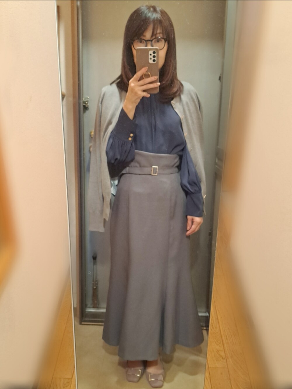 グレー系のスカート、ブルー系のシャツ/ブラウス、ベージュ系のパンプスを着用したレディースの秋コーディネートの2枚目の写真