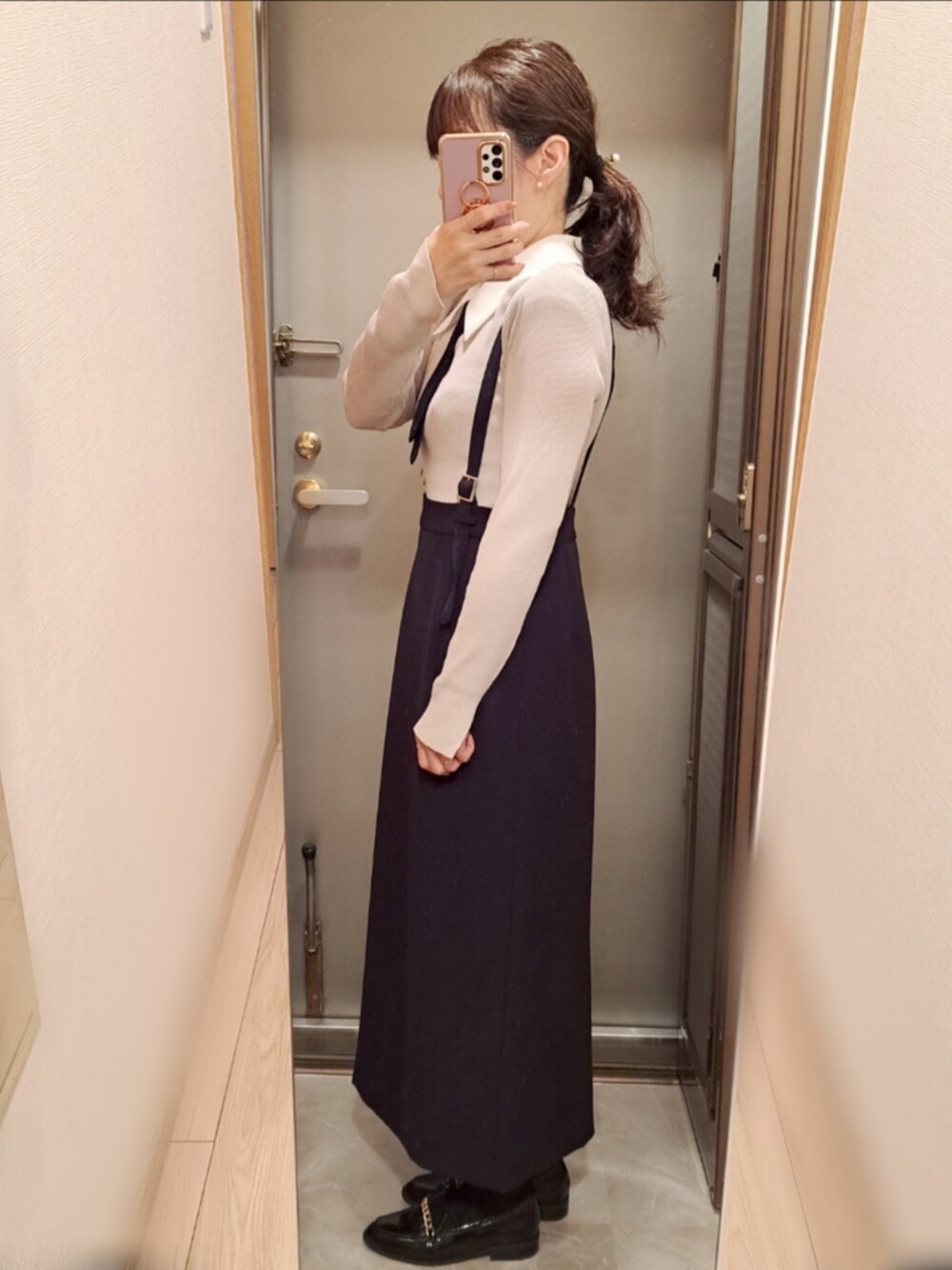 グレー系のニット/セーター、ブラック系のスカート、ブラック系のローファーを着用したレディースの春コーディネートの2枚目の写真