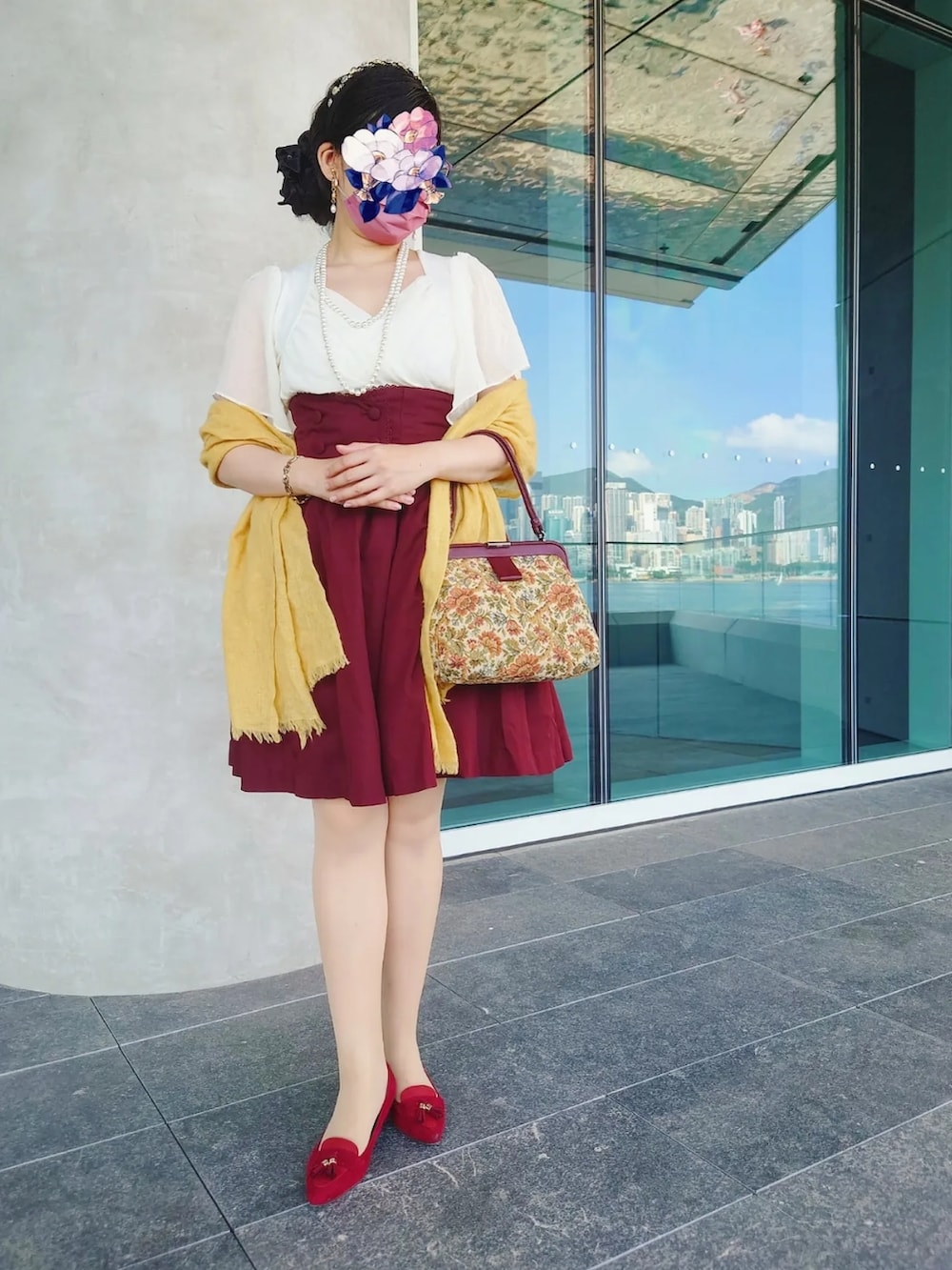 レッド系のスカート、ブラウン系のハンドバッグ、レッド系のパンプスを着用したレディースの夏コーディネートの2枚目の写真