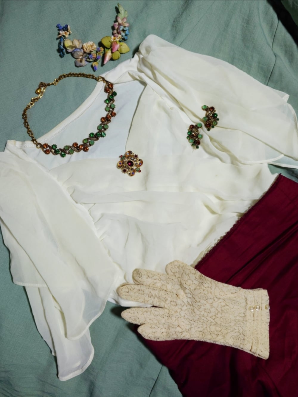 レッド系のスカート、シルバー系のブーティ、グリーン系のネックレスを着用したレディースの夏コーディネートの2枚目の写真