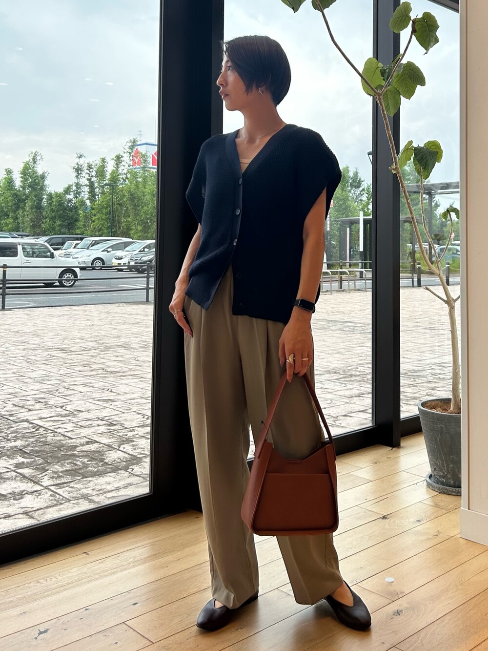 ブルー系のベスト、ブラウン系のハンドバッグ、ベージュ系のその他パンツを着用したレディースの秋コーディネートの3枚目の写真