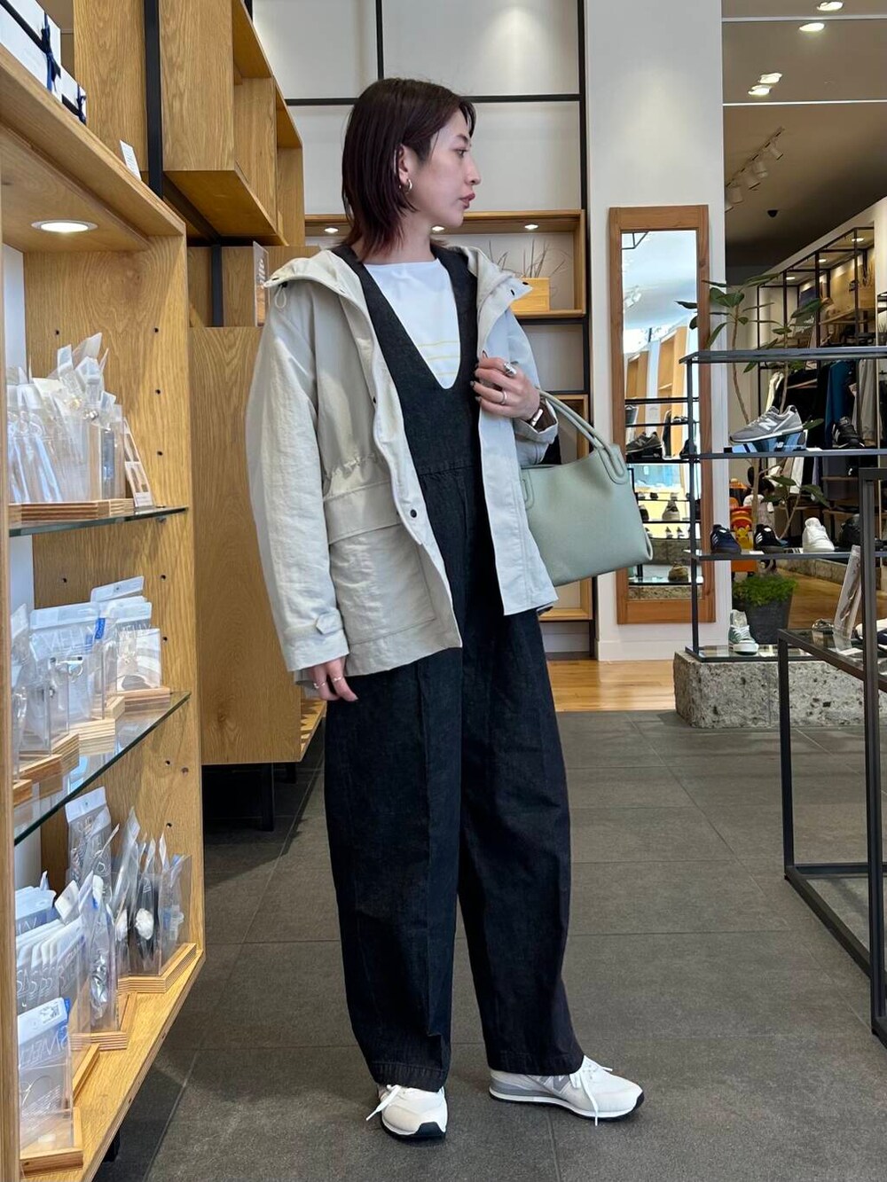 イエロー系のニット/セーター、グリーン系のハンドバッグ、ベージュ系のマウンテンパーカーを着用したレディースの春コーディネートの2枚目の写真