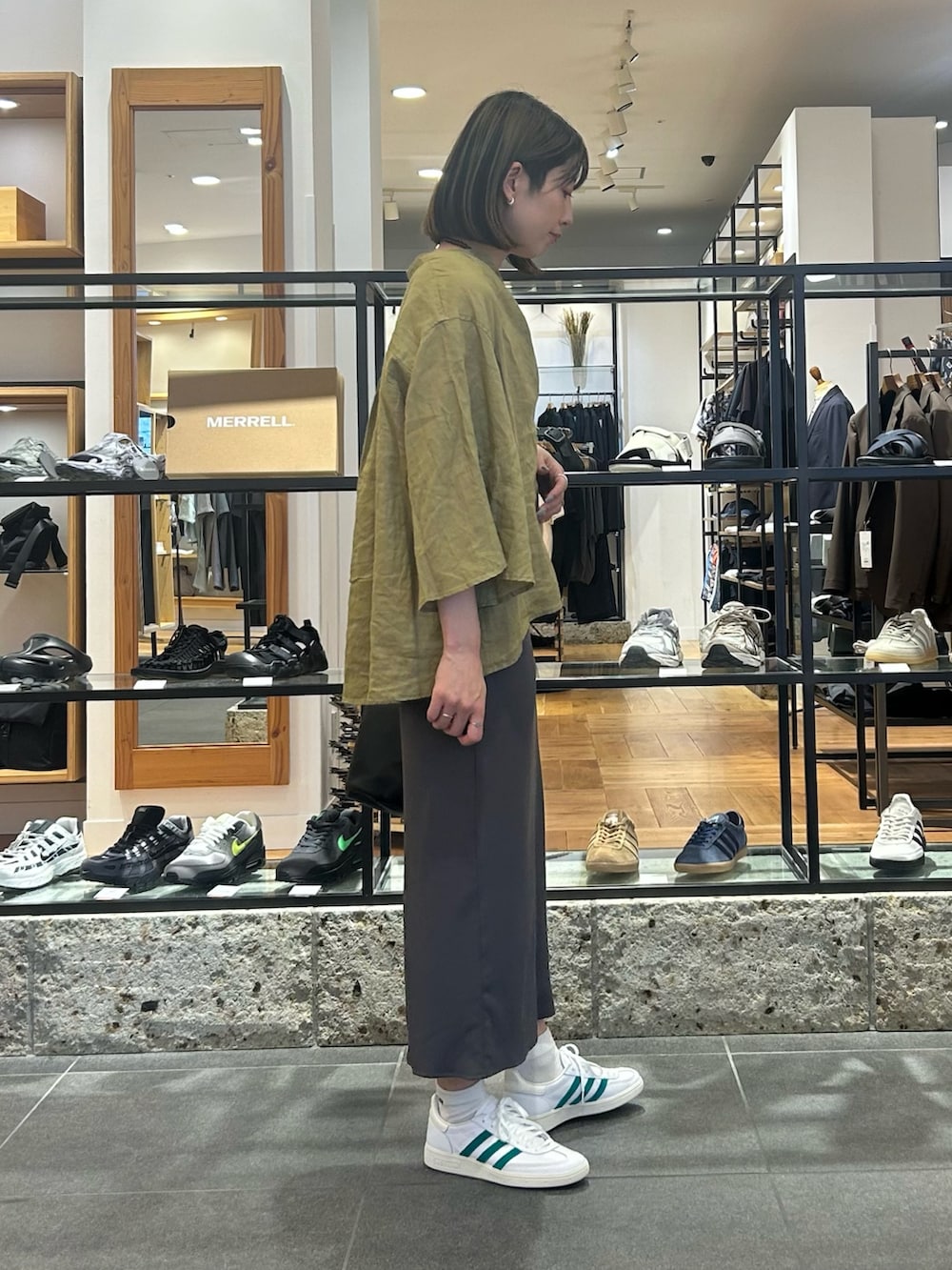 グレー系のスカート、ホワイト系のスニーカー、ブラック系のショルダーバッグを着用したレディースの春コーディネートの4枚目の写真