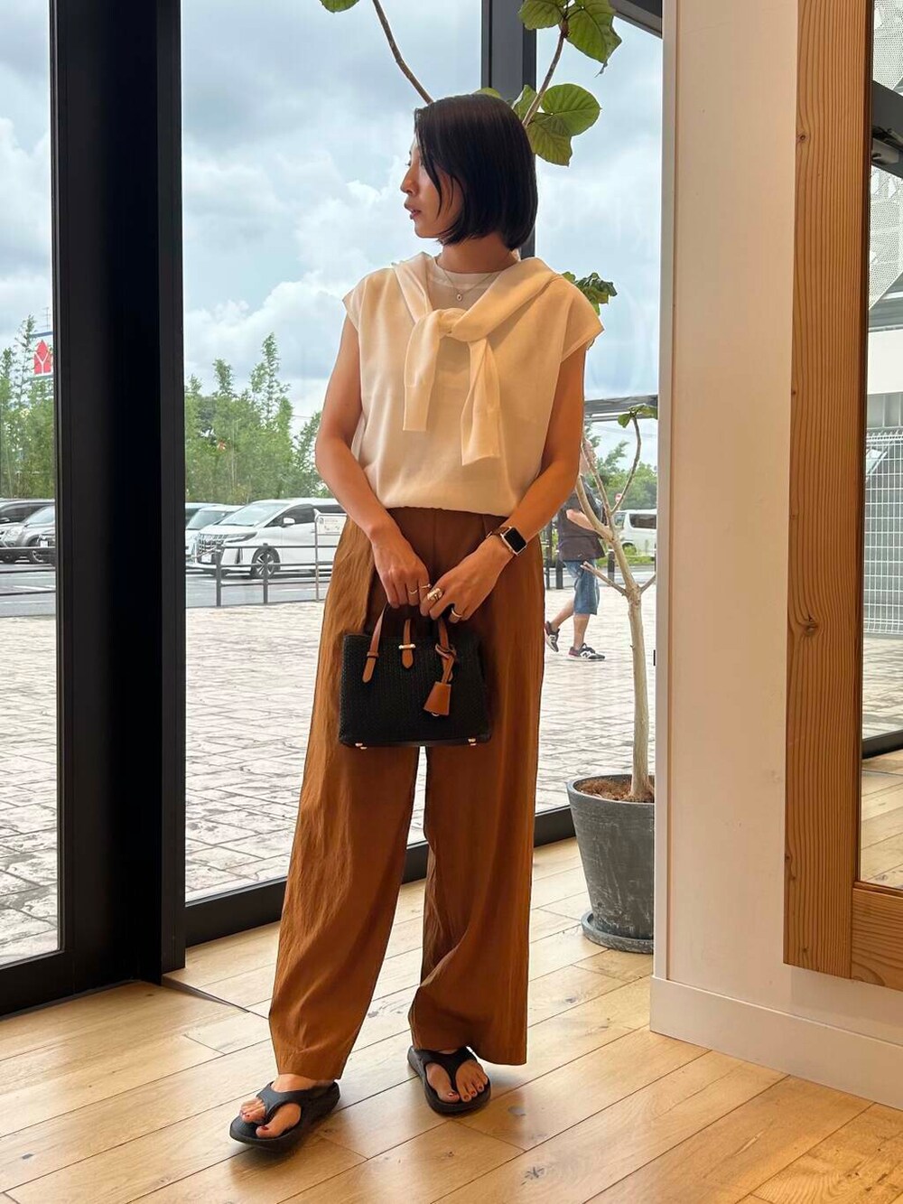 ブラック系のサンダル、ブラック系のトートバッグ、ホワイト系のニット/セーターを着用したレディースの夏コーディネートの2枚目の写真