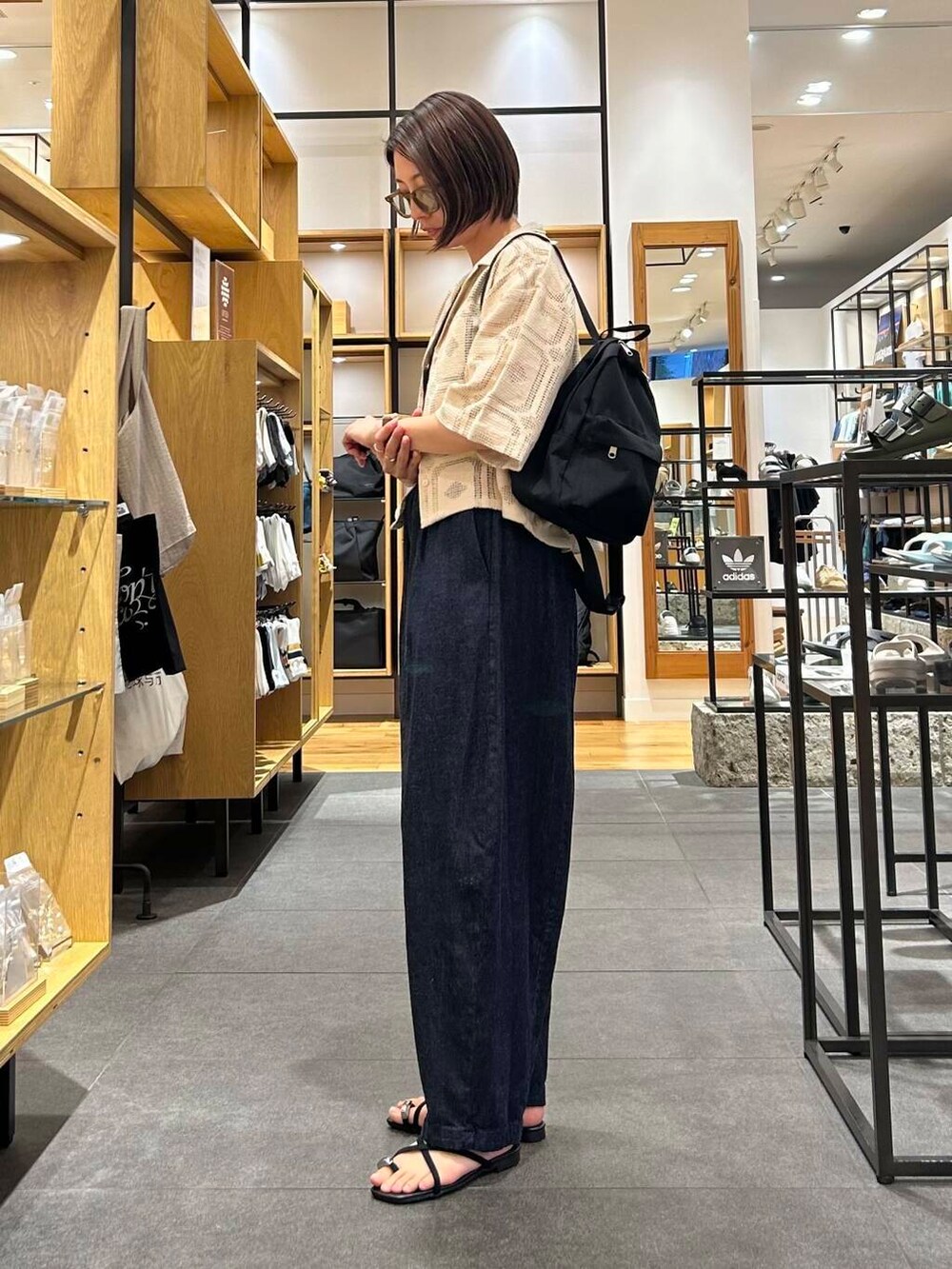 ブルー系のデニムパンツ、ブラック系のバックパック/リュック、ブラック系のタンクトップを着用したレディースの夏コーディネートの3枚目の写真