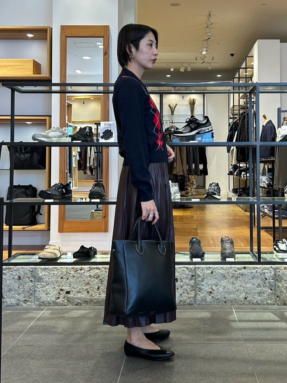 ブラウン系のスカート、ブルー系のニット/セーター、ブラック系のトートバッグを着用したレディースの秋コーディネートの4枚目の写真