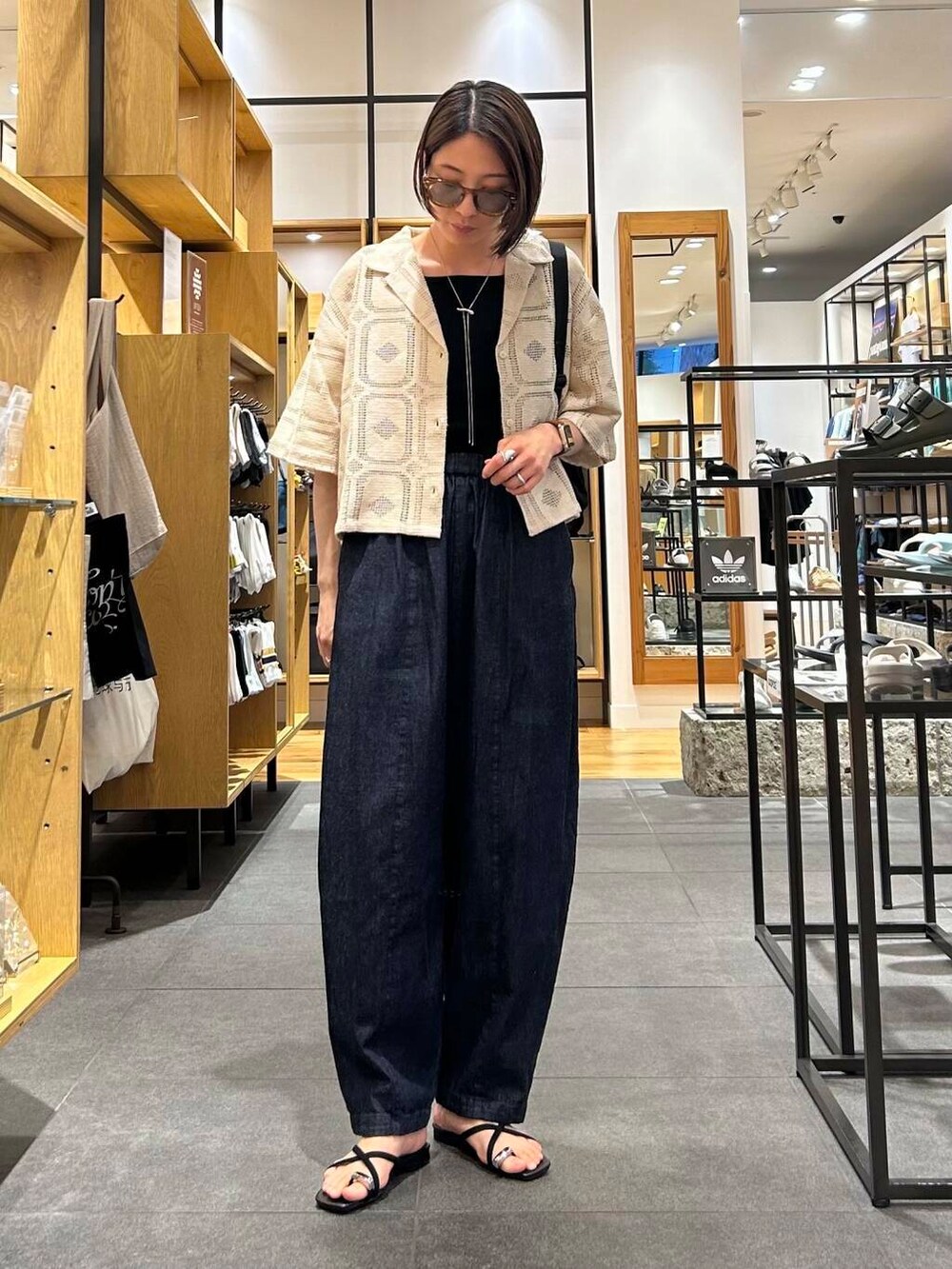 ブルー系のデニムパンツ、ブラック系のバックパック/リュック、ブラック系のタンクトップを着用したレディースの夏コーディネートの2枚目の写真