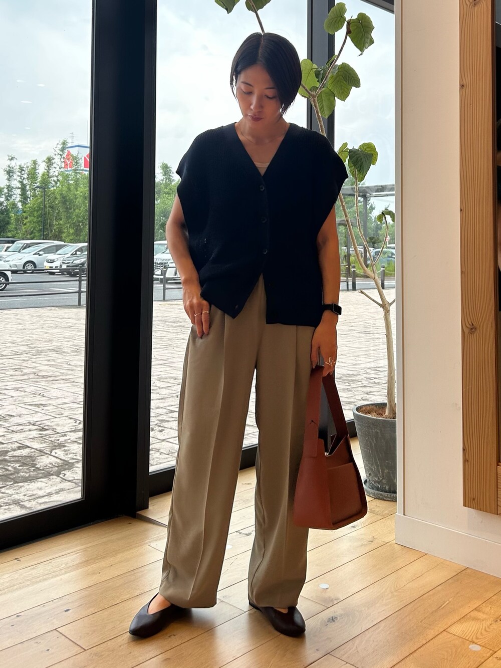 ブルー系のベスト、ブラウン系のハンドバッグ、ベージュ系のその他パンツを着用したレディースの秋コーディネートの4枚目の写真