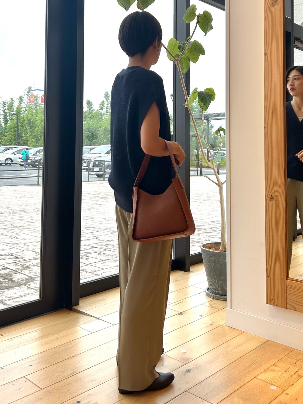 ブルー系のベスト、ブラウン系のハンドバッグ、ベージュ系のその他パンツを着用したレディースの秋コーディネートの5枚目の写真