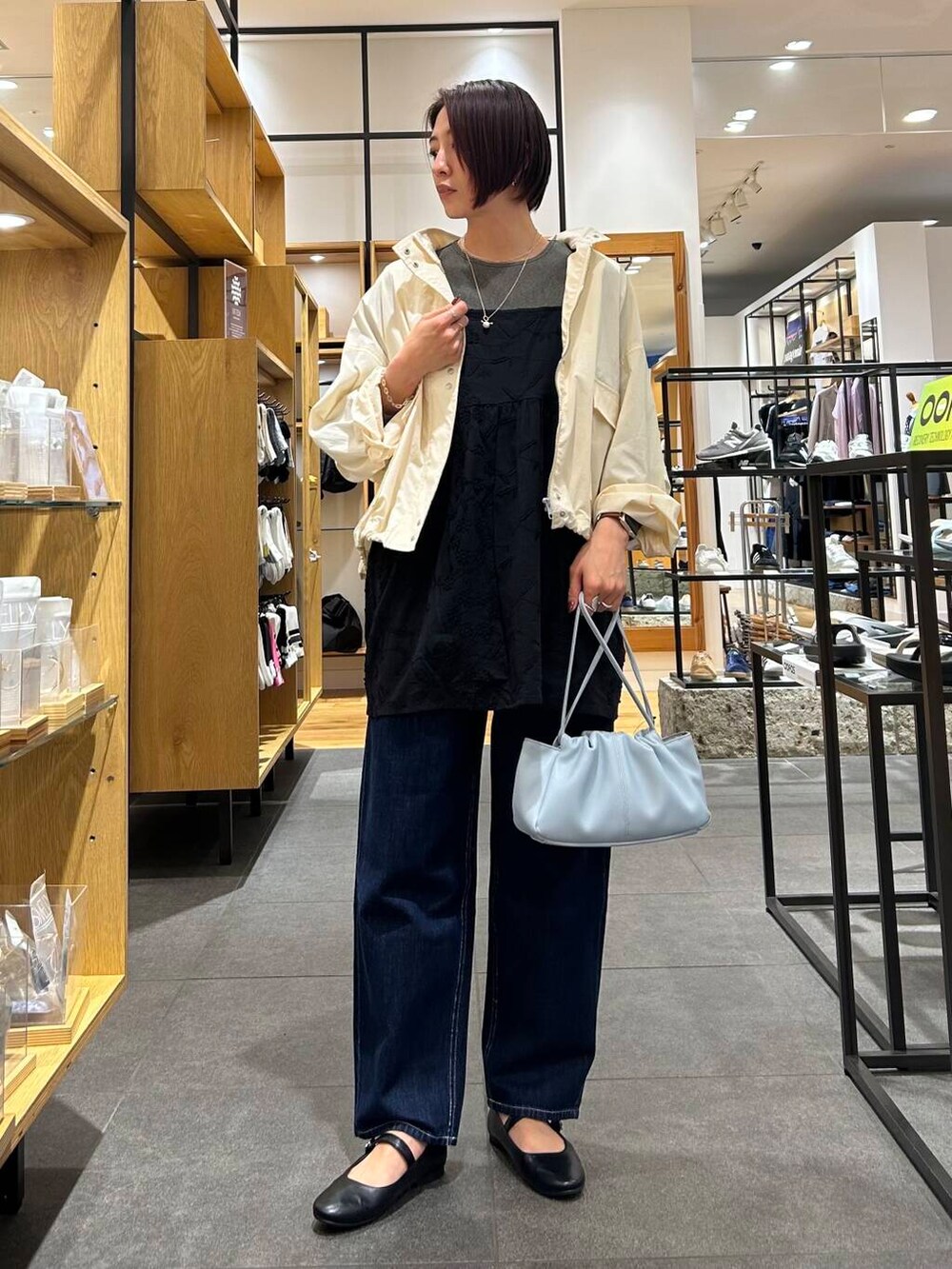 ブルー系のショルダーバッグ、ブラック系のパンプス、ブルー系のデニムパンツを着用したレディースの春コーディネートの2枚目の写真