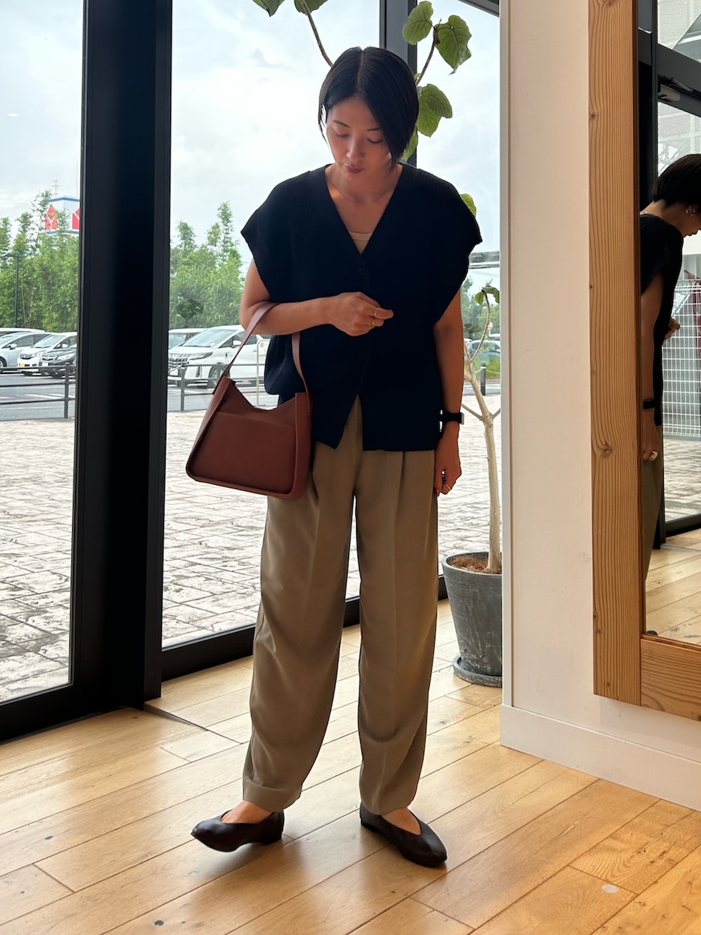 ブルー系のベスト、ブラウン系のハンドバッグ、ベージュ系のその他パンツを着用したレディースの秋コーディネートの2枚目の写真