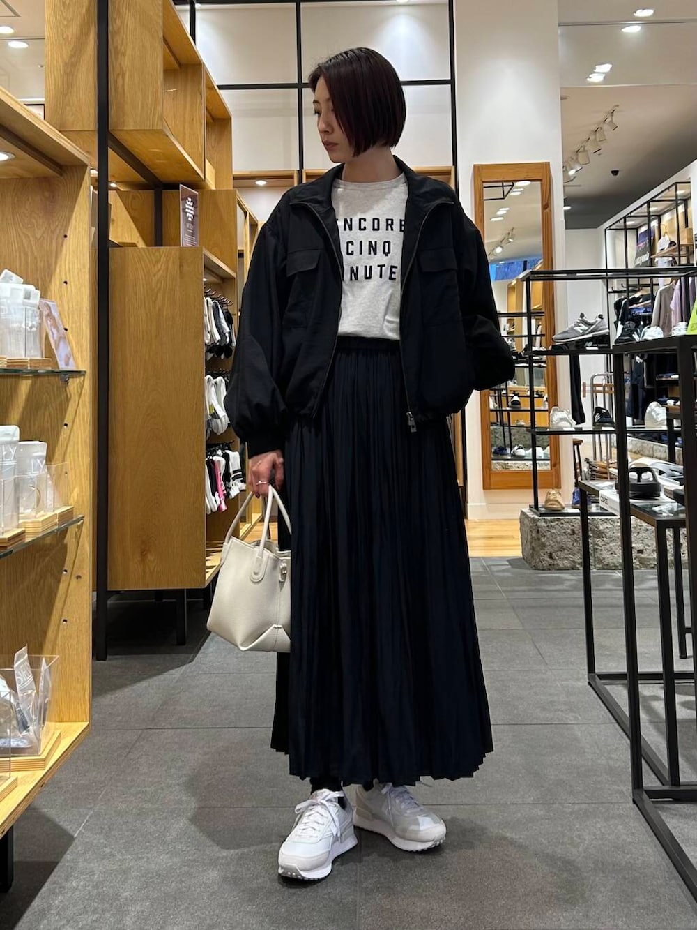 ホワイト系のハンドバッグ、ホワイト系のスニーカー、ブラック系のブルゾンを着用したレディースの春コーディネートの5枚目の写真