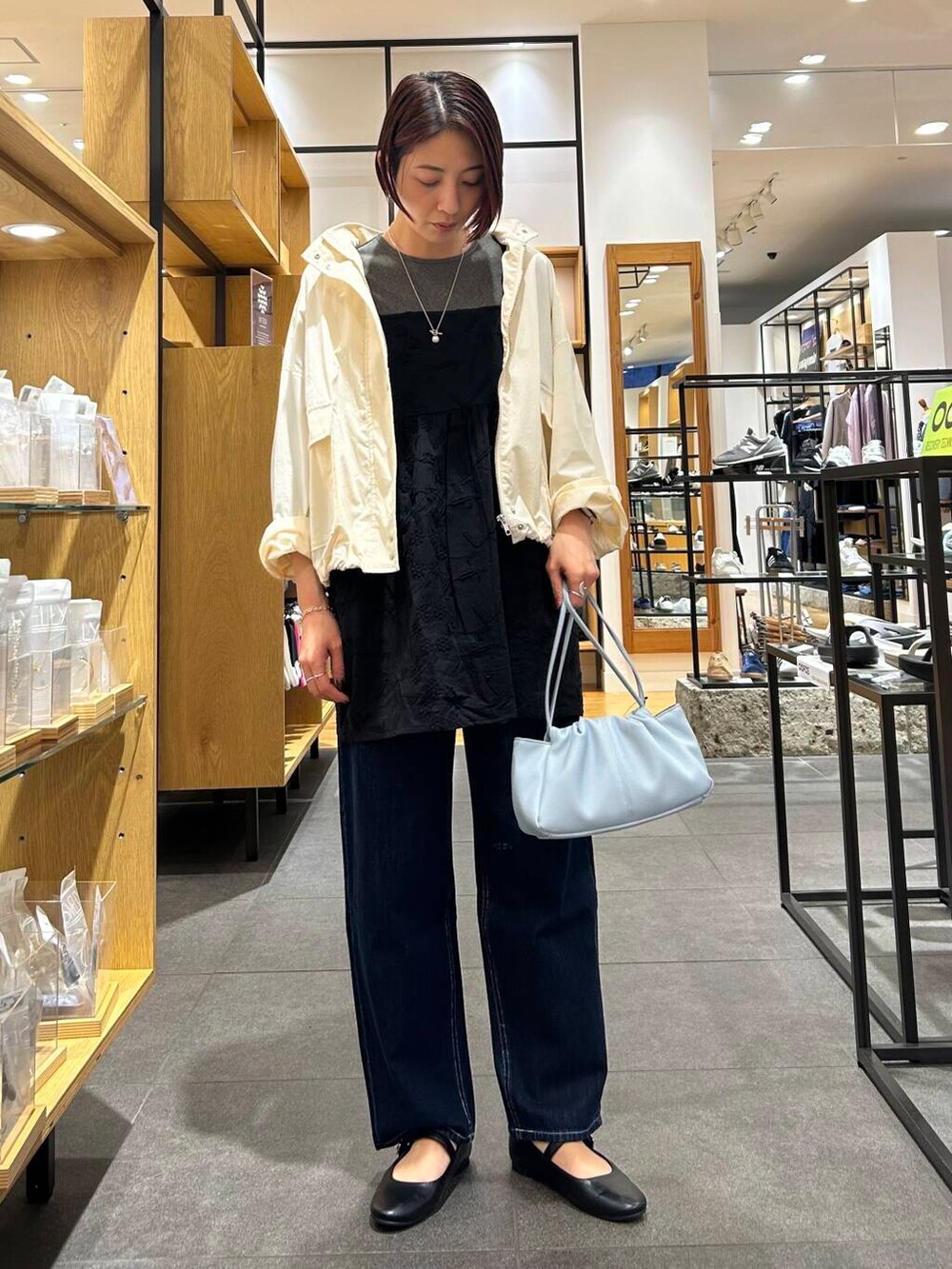 ブルー系のショルダーバッグ、ブラック系のパンプス、ブルー系のデニムパンツを着用したレディースの春コーディネートの3枚目の写真